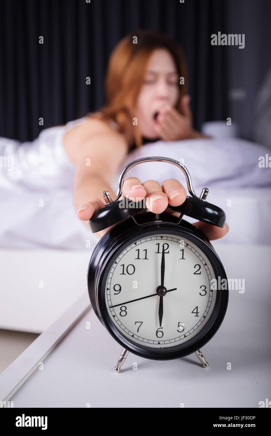 Frau schlafen und Aufwachen bis zum Ausschalten des Weckers morgens Stockfoto