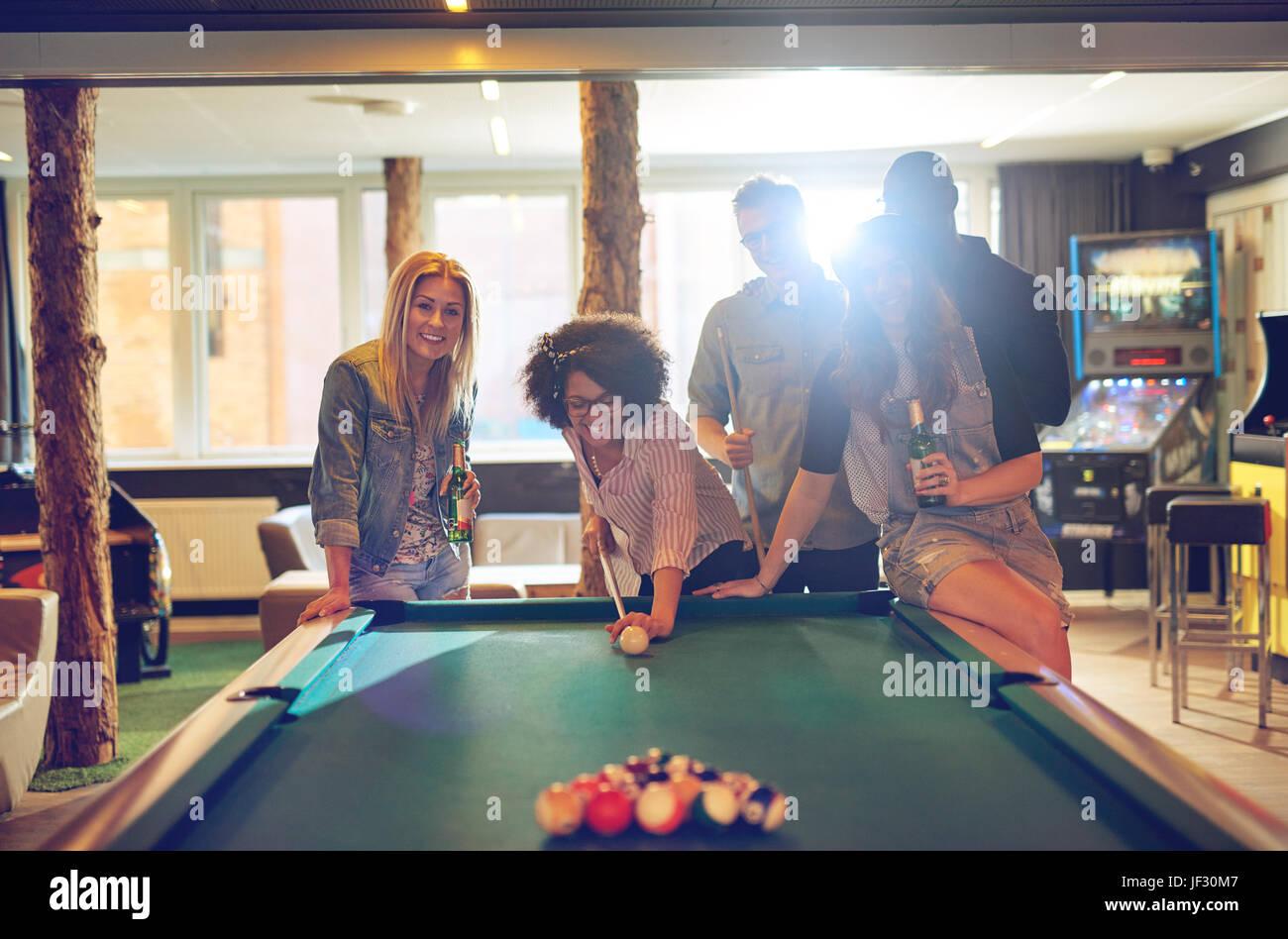 Gruppe von fünf männliche und weibliche Freunde im Spielzimmer Billard zusammen spielen, während Sie lachen und trinken Bier Stockfoto