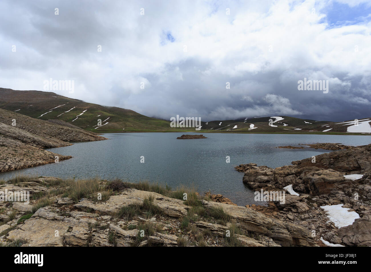 Horizontalen Schuss von Mountain Lake umgeben von Pisten fallenden Schnee schmelzen Stockfoto