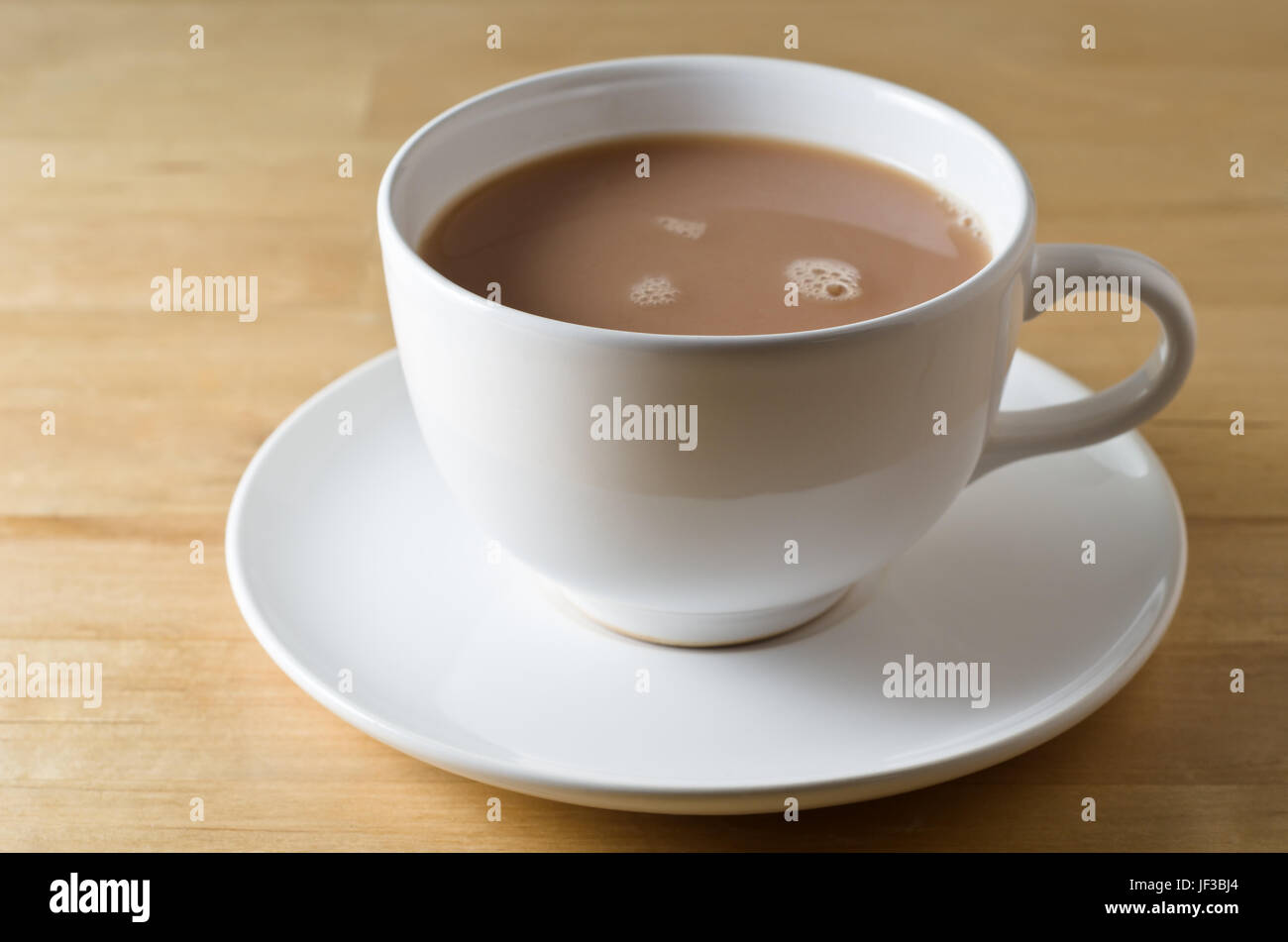 Eine Tasse Tee im Weißware Tasse und Untertasse auf einem leichten Holz (Birke) Tisch.  Querformat (horizontale). Stockfoto