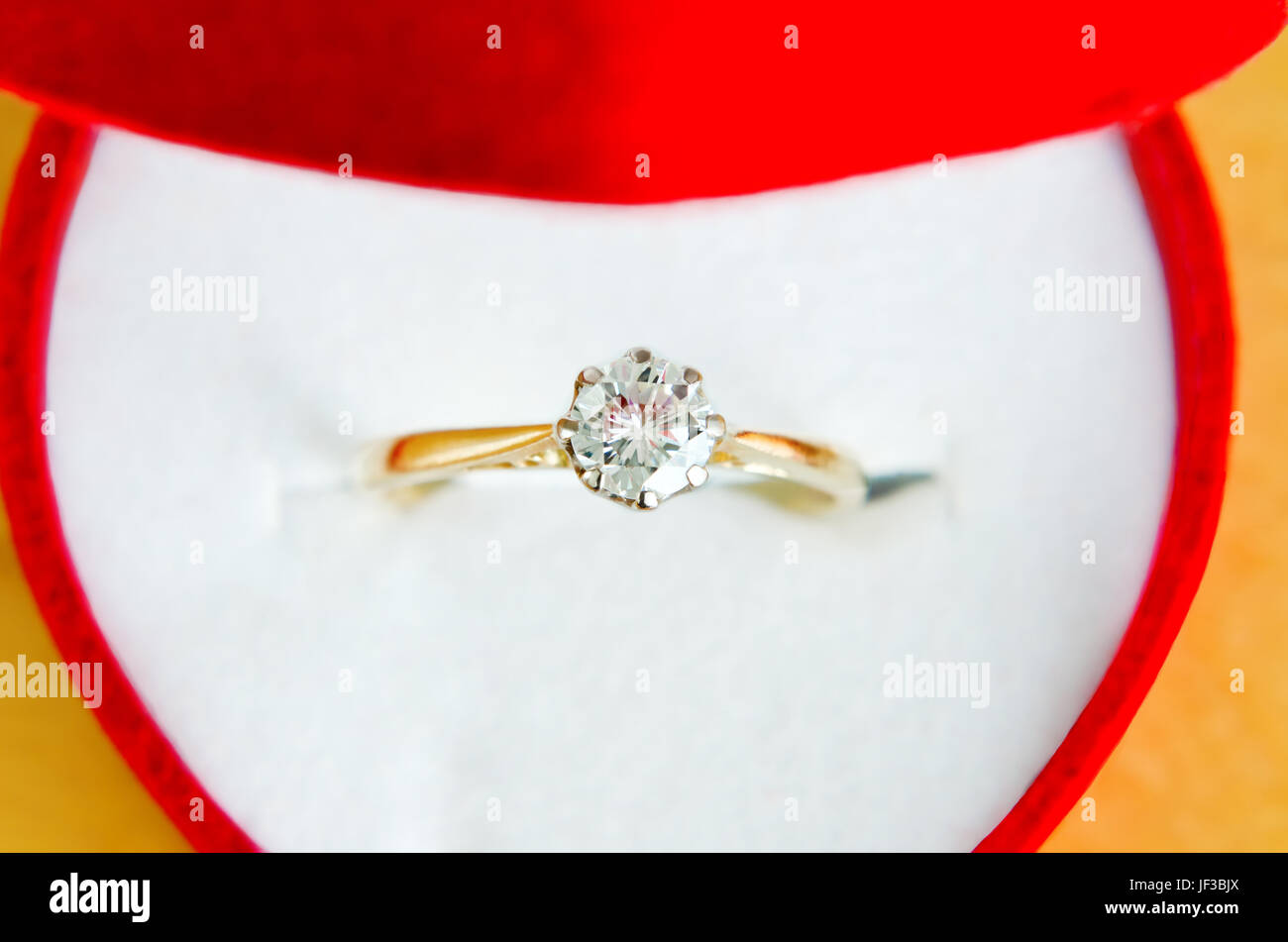 Nahaufnahme (Makro) von gold, Solitär Diamant-Verlobungsring, von oben, in einer offenen roten herzförmige Schachtel mit weißen inneren erschossen. Stockfoto