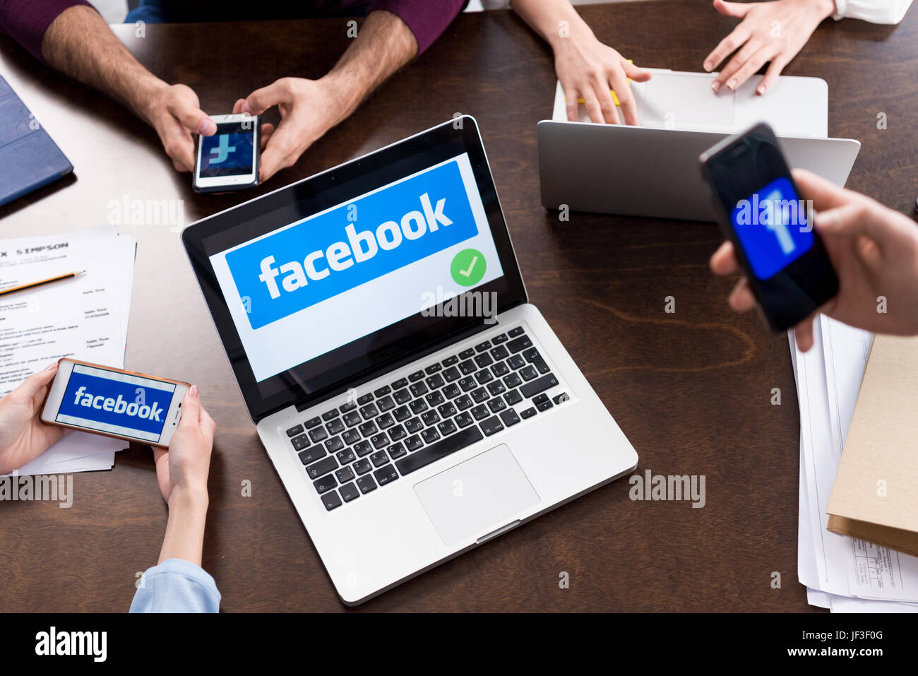 Schuss von Geschäftsleuten mit digitalen Geräten mit Facebook Logo Symbole auf Bildschirmen abgeschnitten Stockfoto