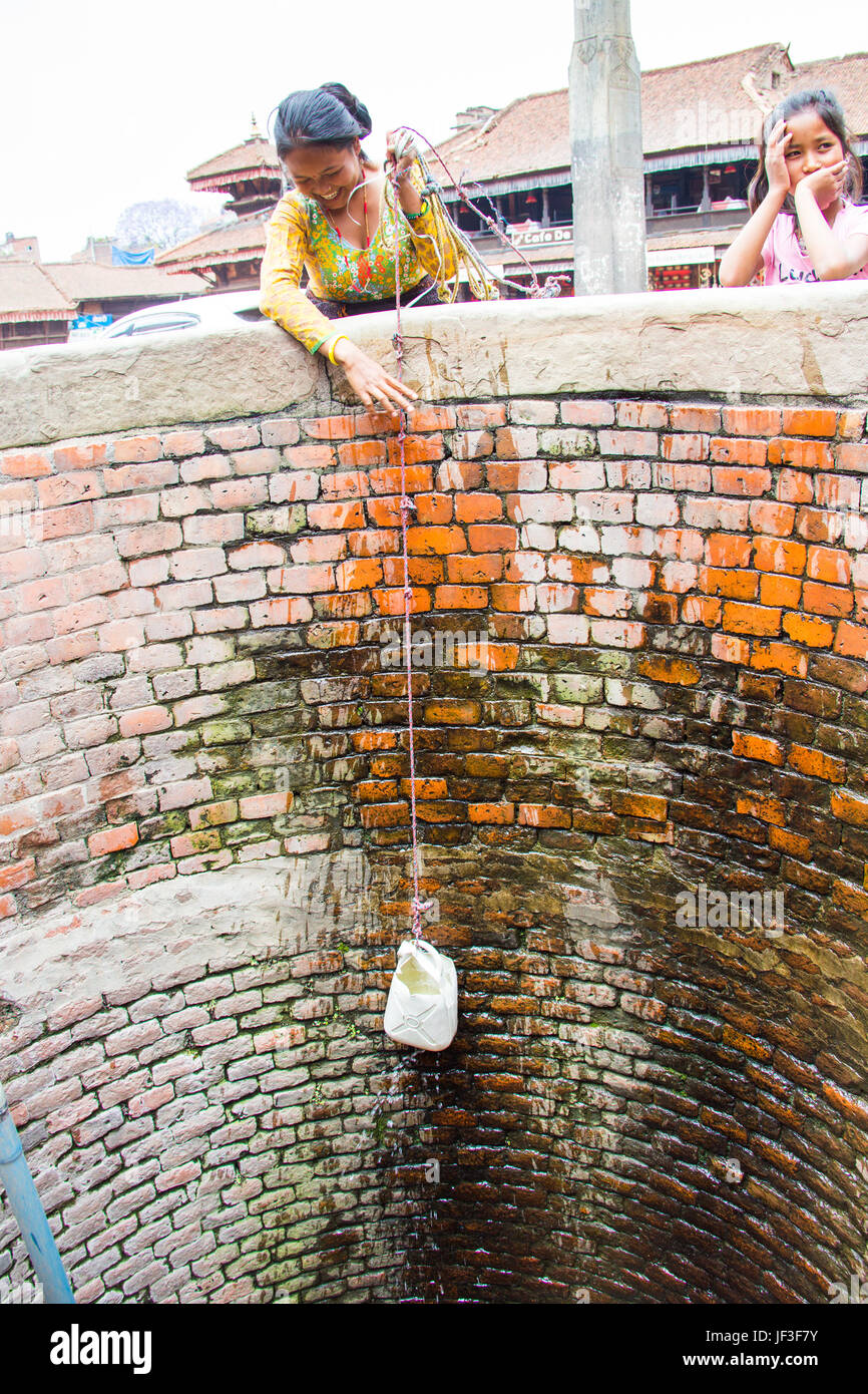 Junge Frau ziehen Wasser aus einem Brunnen in Bhaktapur, Kathmandu, Nepal Stockfoto