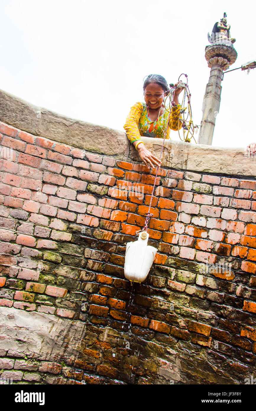 Junge Frau ziehen Wasser aus einem Brunnen in Bhaktapur, Kathmandu, Nepal Stockfoto