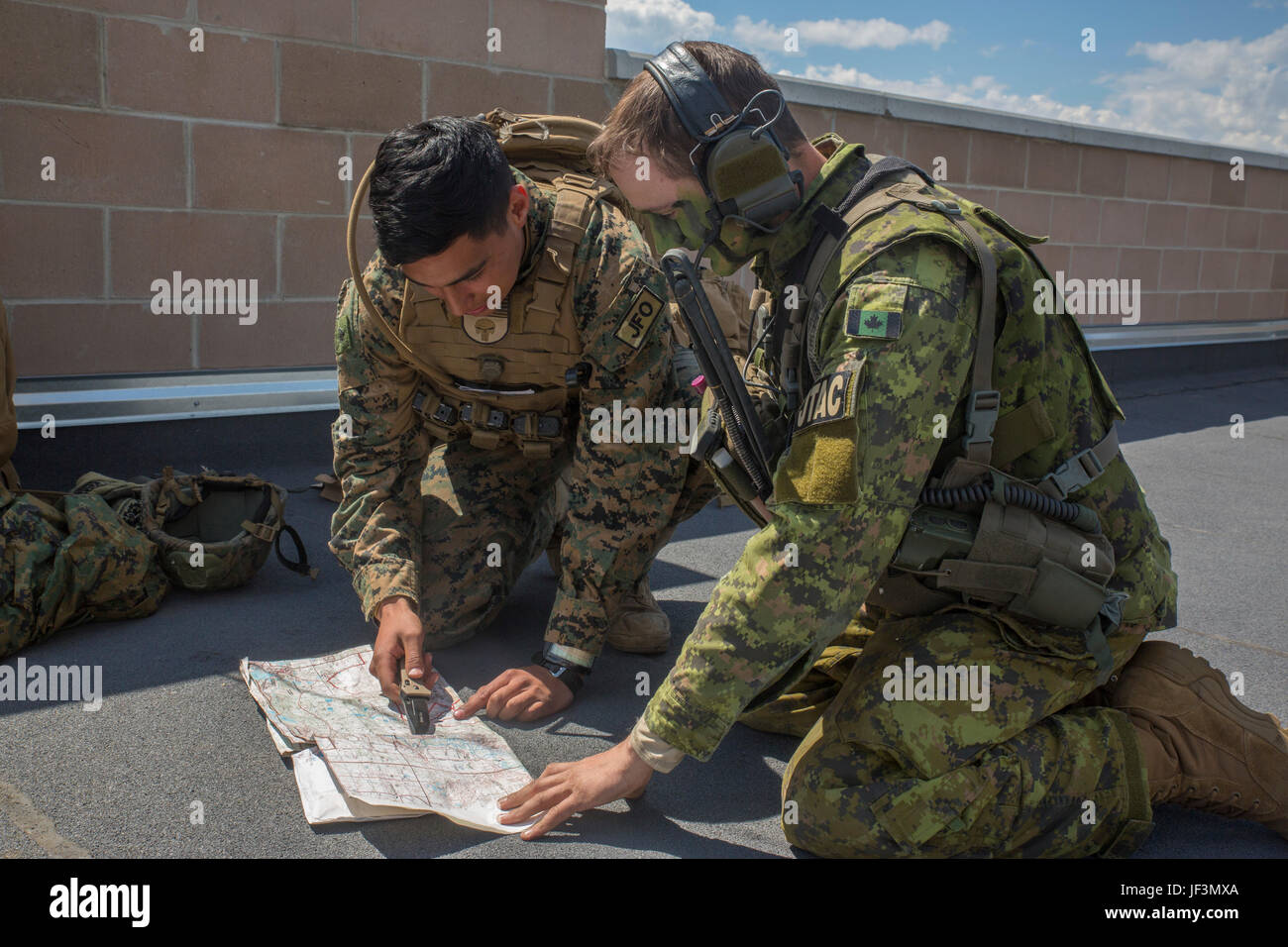 CPL. Daniel A. Reyes (links), einem gemeinsamen Feuer Beobachter mit 3. Brigade, 3. Air Naval Gunfire Liaison Company, Marine Forces Reserve Force Headquarters Gruppe kniet neben Canadian Army Captain Ethan McDonald (rechts), einen gemeinsamen terminal Angriff Controller mit Y Batterie, 2. Regiment, Königliche kanadische Pferd Artillerie und weist auf Zielkoordinaten auf einer Karte im kanadischen Manöver Training Center, Wainwright , Alberta, Kanada, während des Trainings Maple lösen 17, 26. Mai 2017. Während der Übung arbeitete die Marines aus 3. ANGLICO mit der kanadischen Armee, simulierte Artillerie zu vorgeplanten t aufrufen Stockfoto