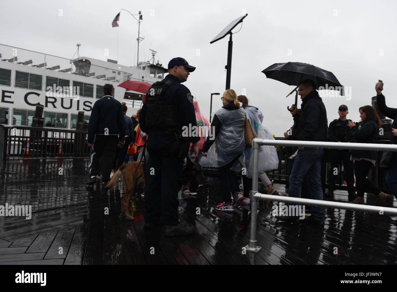 Coast Guard Petty Officer 1st Class Nick Antis aus Maritime Safety und Security-Team NewYork führt einen Sicherheit Sweep mit seinem Hund, Ryder, auf Liberty Island Pier 25. Mai 2017. MSST New York ist eines der Coast Guard Anti-Terror-Teams eingerichtet, um lokalen maritimen Ressourcen zu schützen und zu Großveranstaltungen einschließlich 29. Fleet Week New York zu unterstützen. (Foto: U.S. Coast Guard Petty Officer 3rd Class Frank Iannazzo-Simmons) Stockfoto