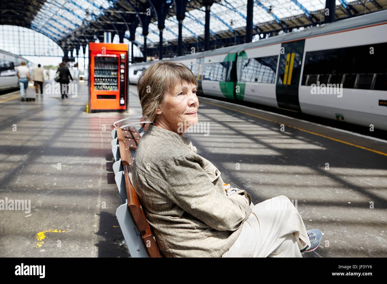 Ältere Frau sitzt am Bahnhof Stockfoto