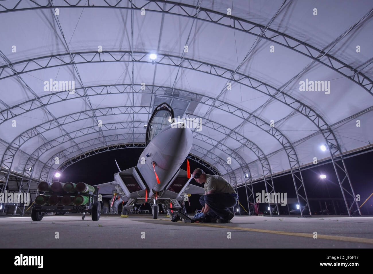 Ein US-Air Force Crewchief zugewiesen der 27. Kämpfer-Flügel führt eine Prüfung auf eine f-22 Raptor auf gemeinsamer Basis Langley-Eustis, Virginia, 27. Juni 2017. Die neu erbaute Sonne Unterstände haben Einbauleuchten, die das Flugzeug, die sind ausschließlich auf Solarstrom lief zu beleuchten. (U.S. Air Force Photo/Flieger 1. Klasse Tristan Biese) Stockfoto