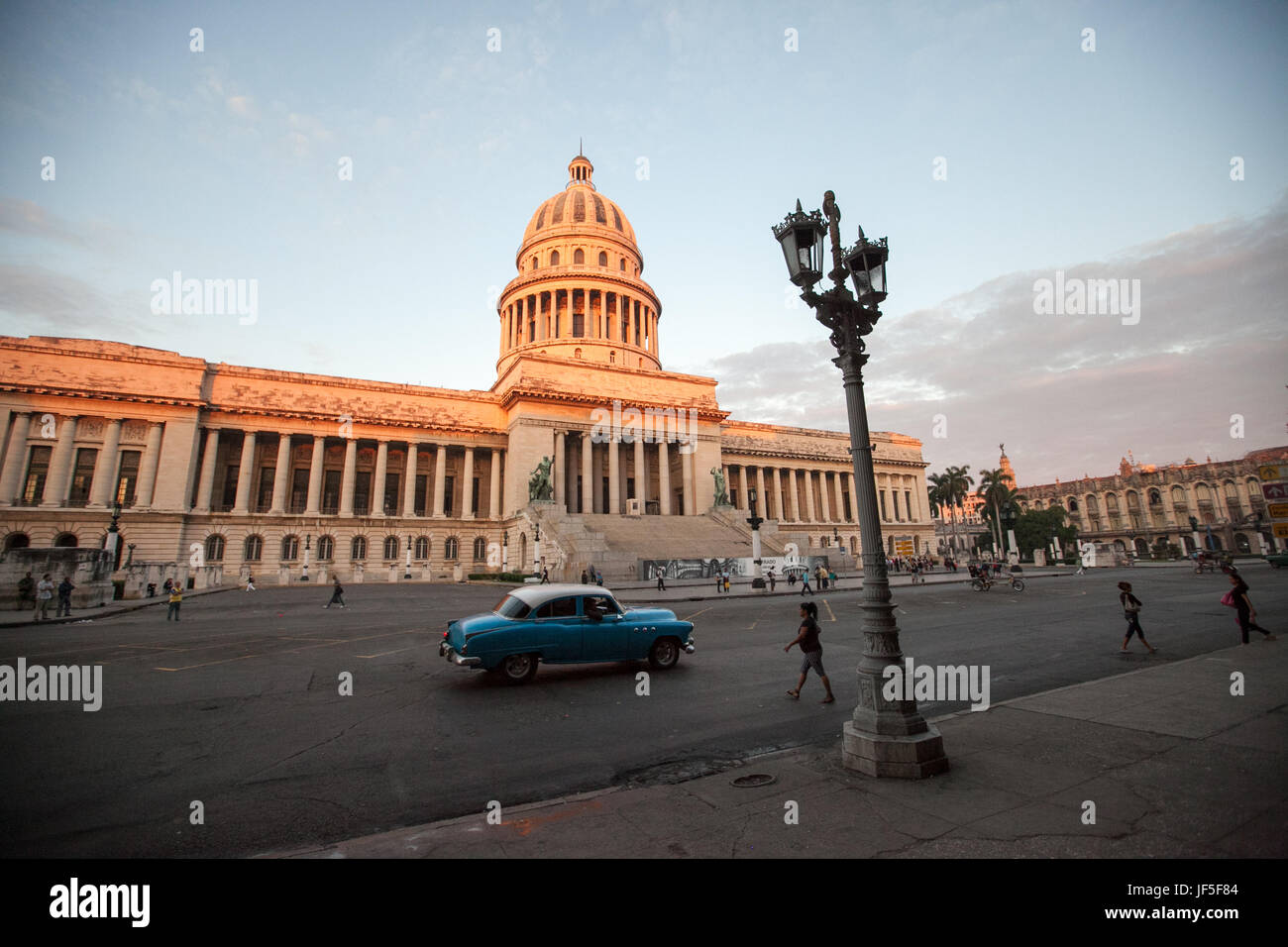 Menschen gehen die Straßen und ein amerikanischen Oldtimer fährt vorbei El Capitolio Gebäude im Zentrum von Havanna. Stockfoto