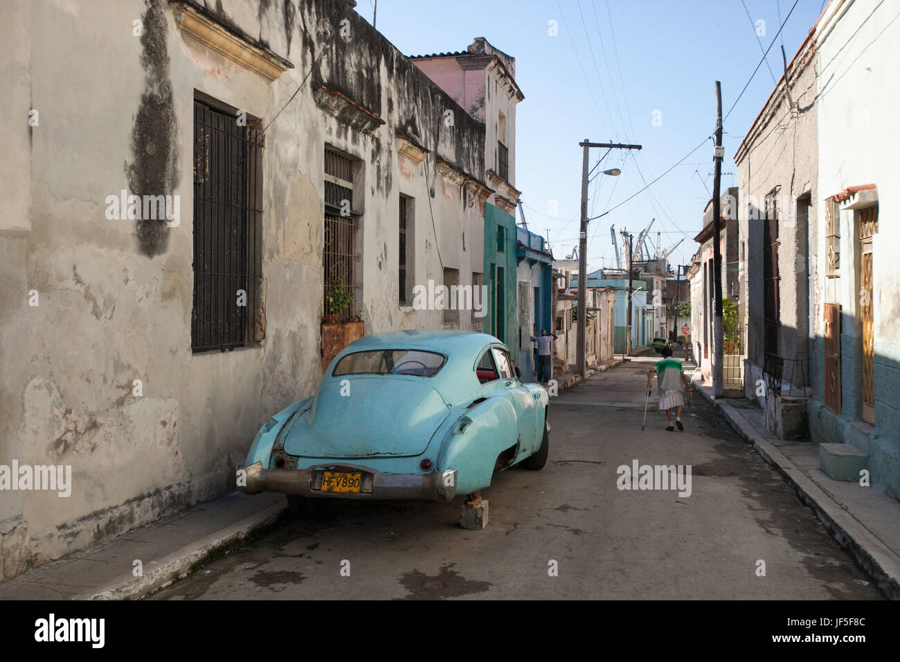 Auf einer Straße in der Innenstadt von Havanna beruht ein amerikanischen Oldtimer auf ein Betonklotz, wie eine Frau vorbeigeht. Stockfoto