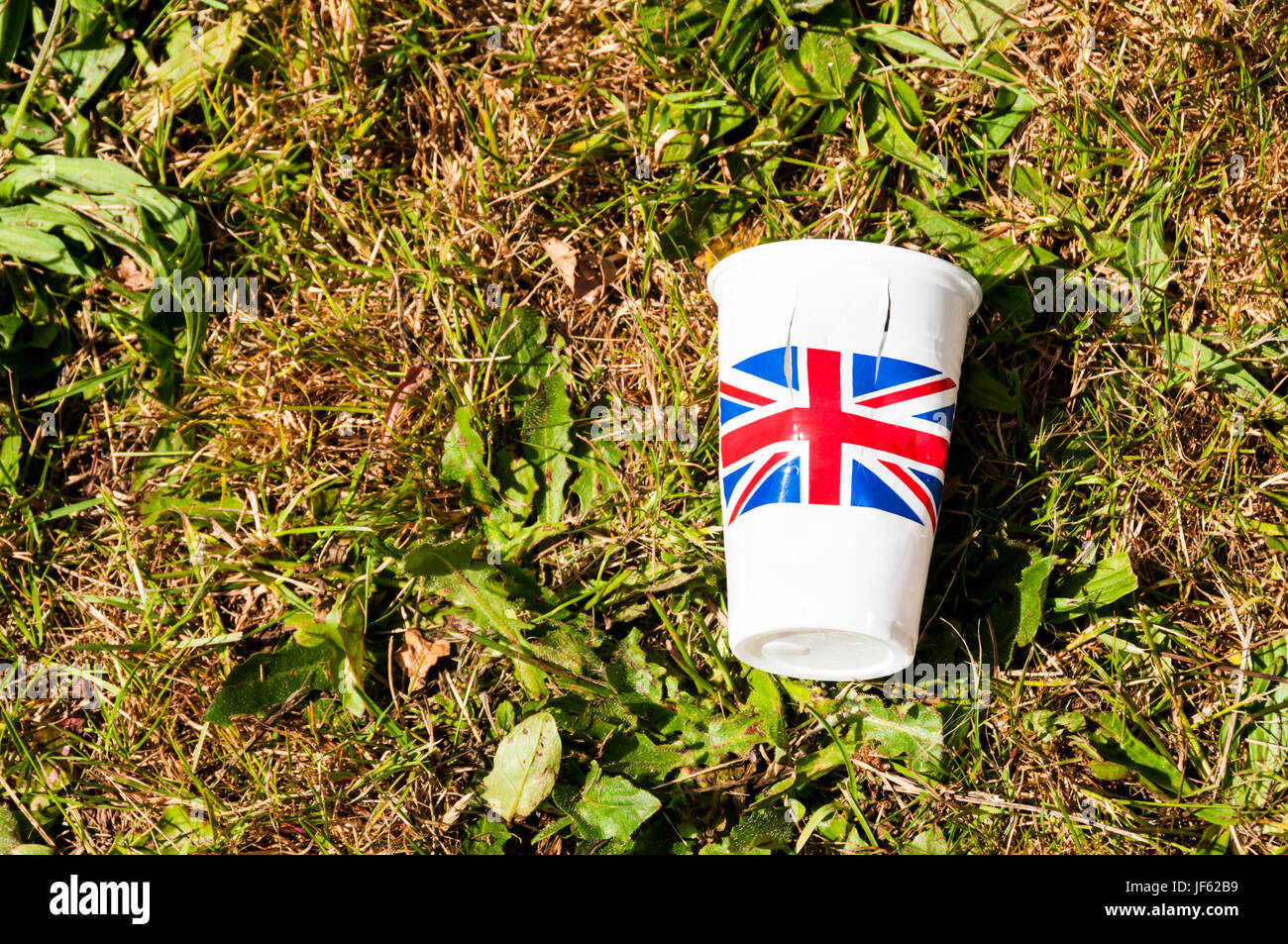 Einen leeren Plastikbecher bedruckt mit dem Union Jack auf dem Rasen liegen. Stockfoto
