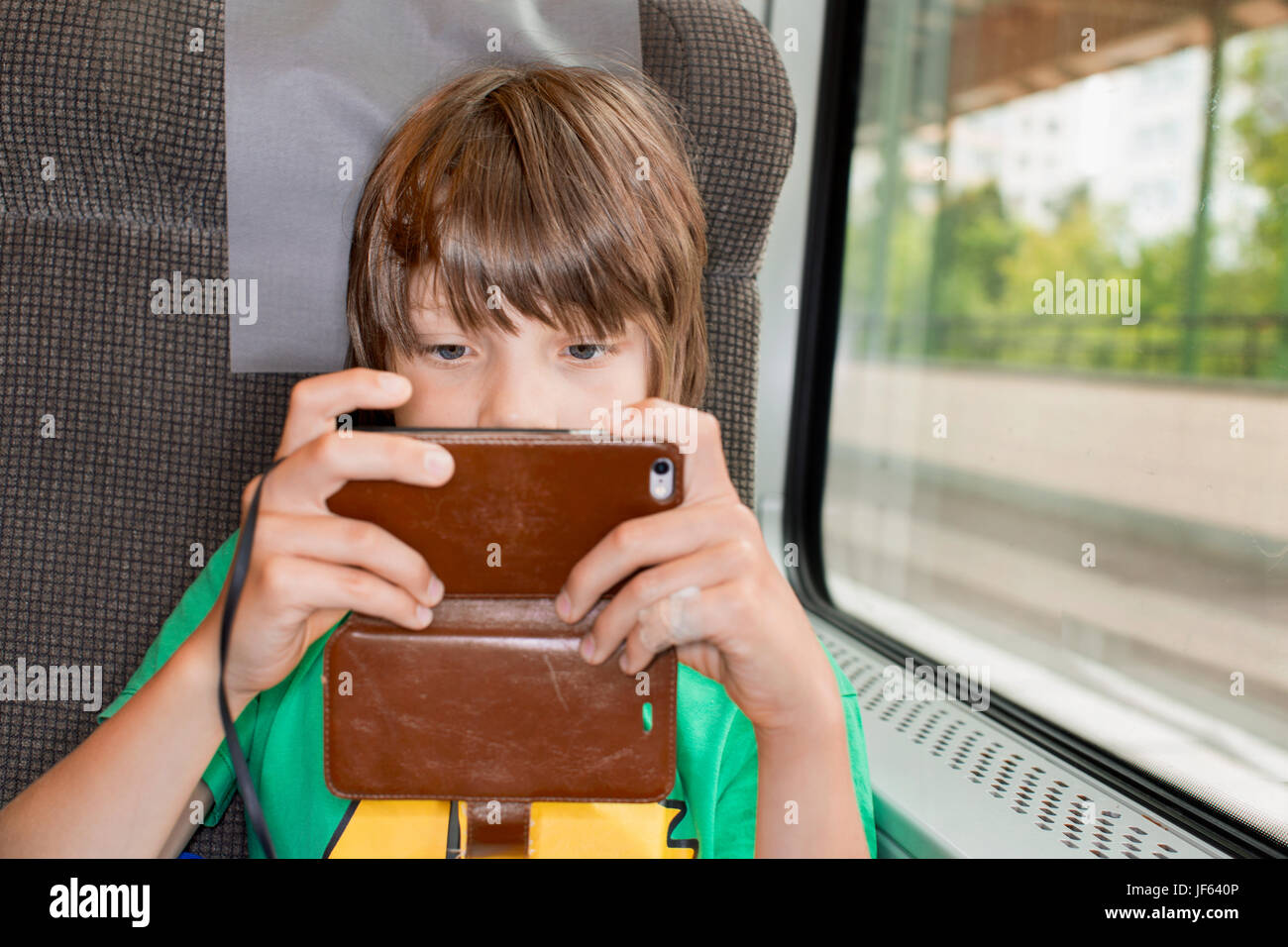 Junge im Zug mit Handy Stockfoto