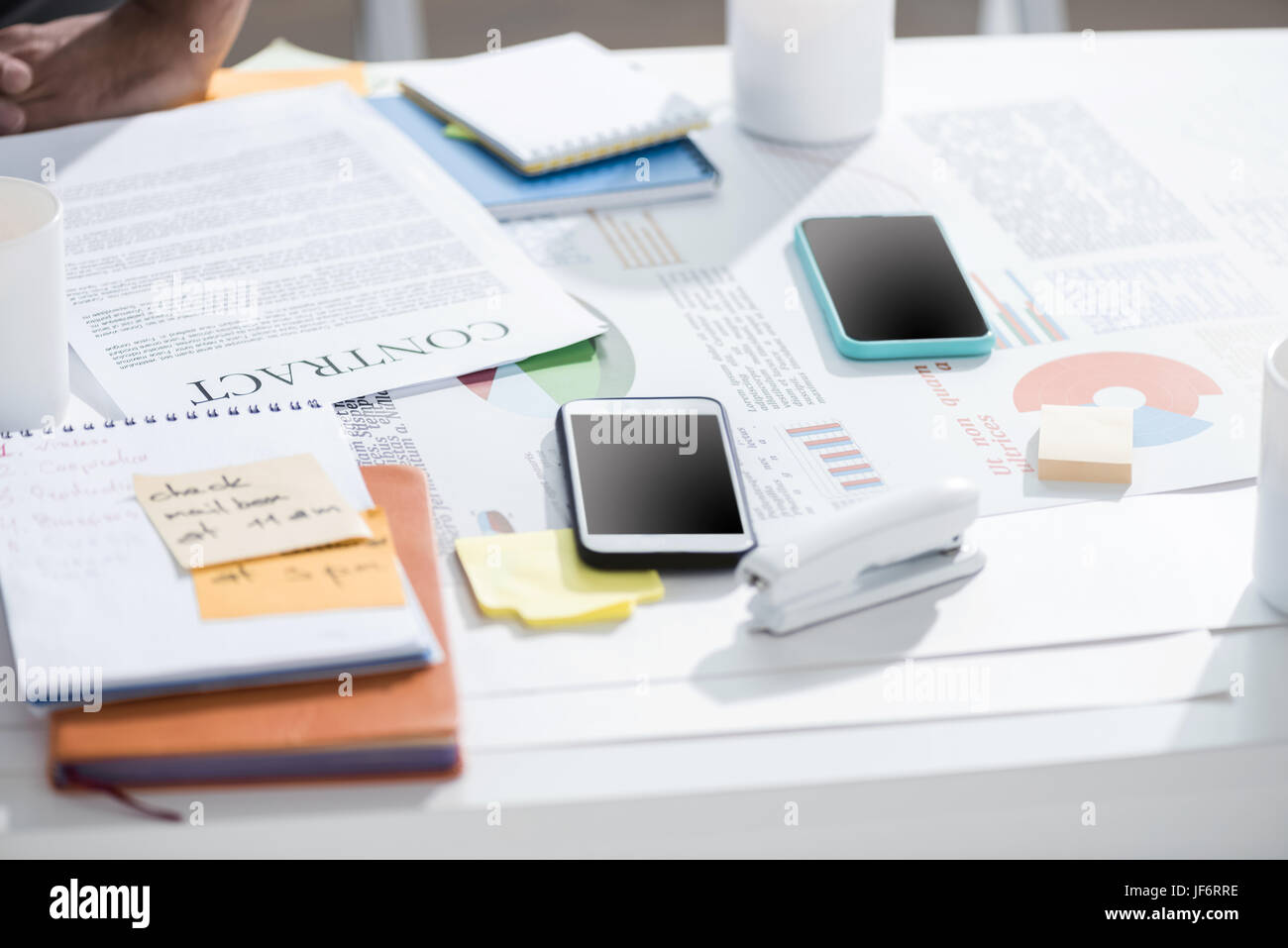 Smartphones mit Vertrag und Notebook mit Hefter auf Tisch im modernen Büro, Betriebsstätte Stockfoto