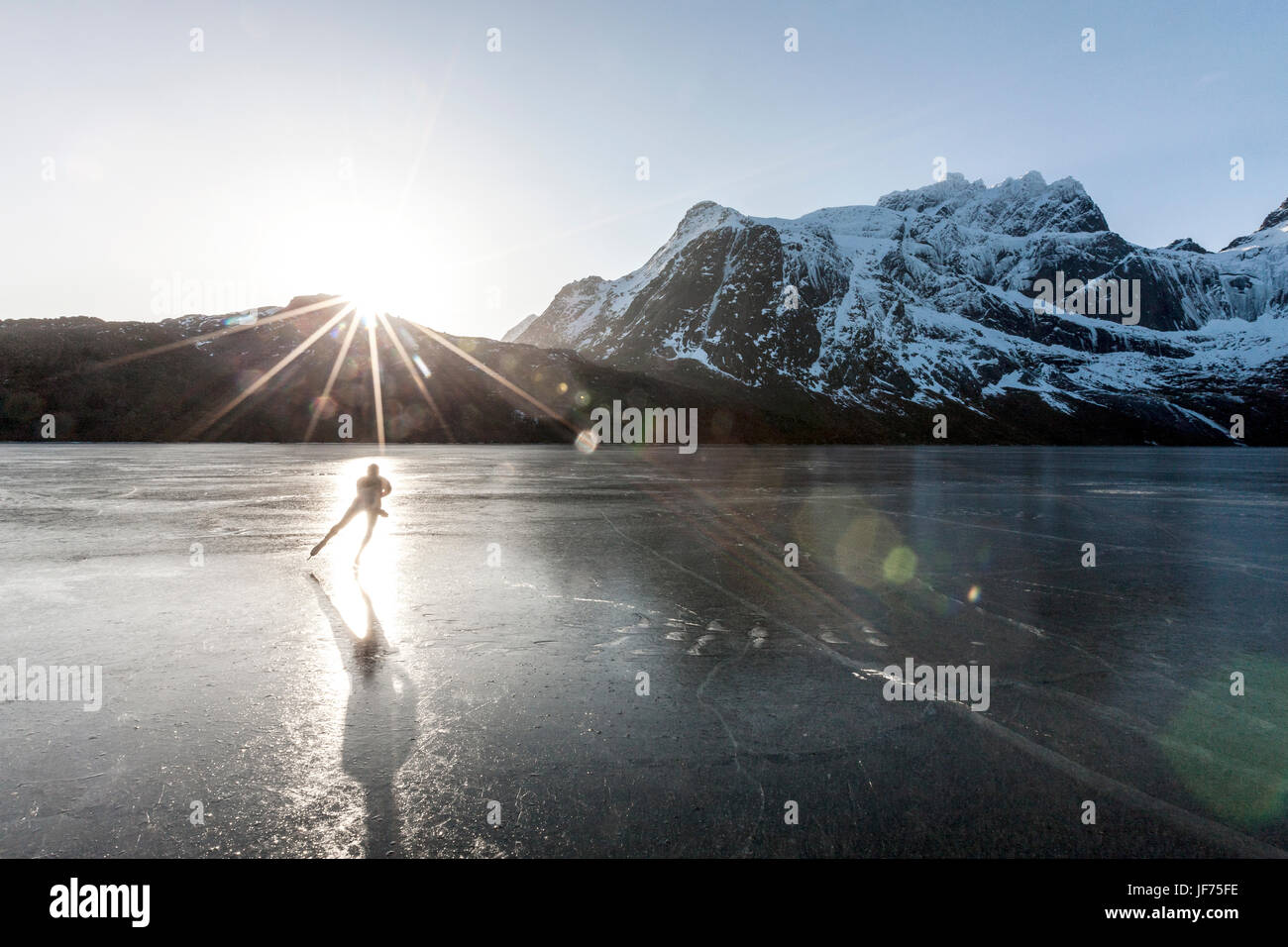 Mann, Schlittschuhlaufen auf zugefrorenen See bei Sonnenuntergang Stockfoto