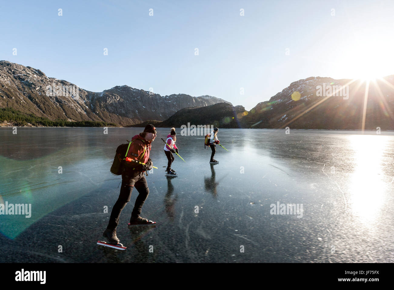 Freunden Schlittschuhlaufen auf zugefrorenen See bei Sonnenuntergang Stockfoto