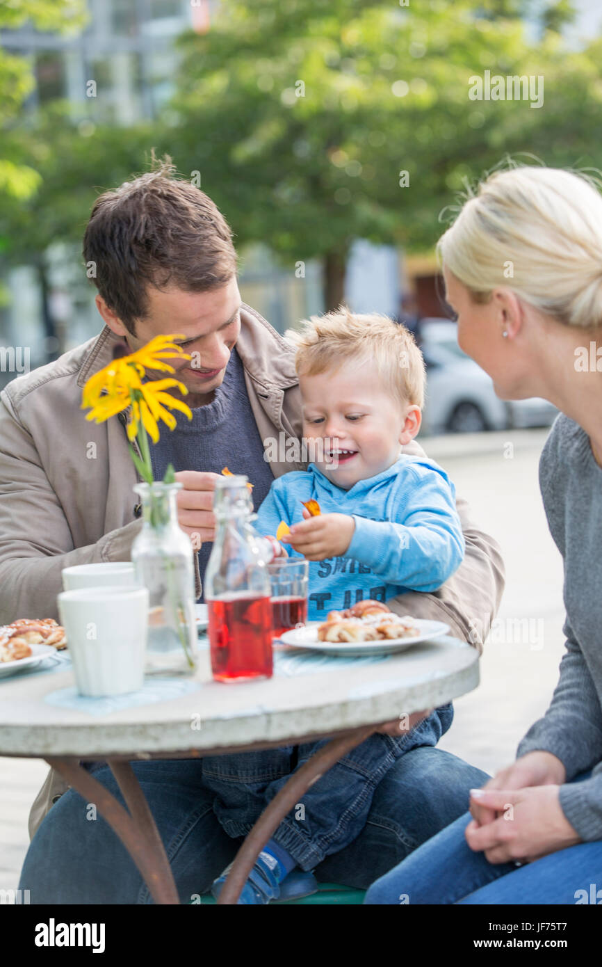 Eltern mit Sohn essen Kuchen im Straßencafé Stockfoto