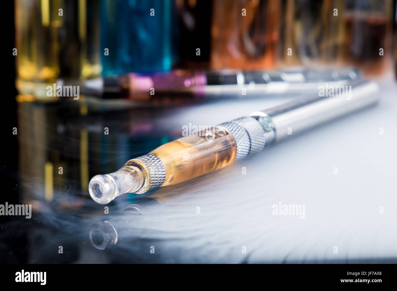 Elektronische Zigarette mit e-Liquid-Flaschen im Hintergrund Stockfoto
