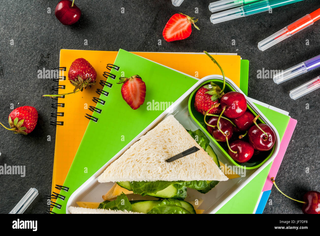 Zurück zur Schule. Ein herzhaftes gesundes Schulessen in einer Box: Sandwiches mit Gemüse und Käse, Beeren und Früchte (Äpfel) mit Notebooks, farbigen Stift Stockfoto