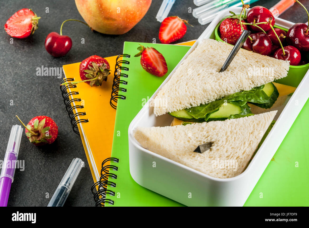 Zurück zur Schule. Ein herzhaftes gesundes Schulessen in einer Box: Sandwiches mit Gemüse und Käse, Beeren und Früchte (Äpfel) mit Notebooks, farbigen Stift Stockfoto