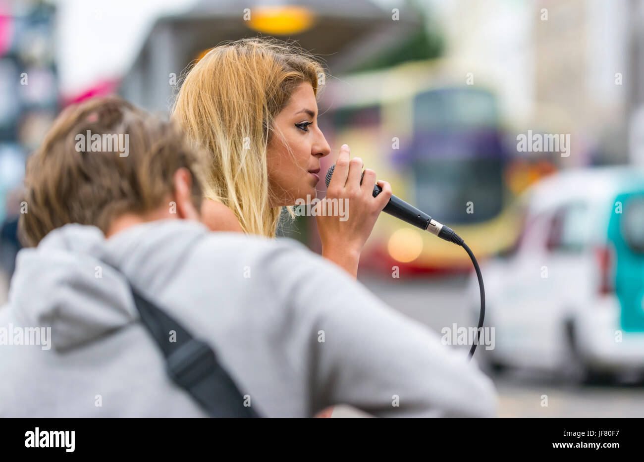 Frau singt auf der Straße mit einem Gitarristen. Als Straßenmusikant. Straßenmusiker. Straßenmusikanten. Weibliche Straßenmusiker. Stockfoto