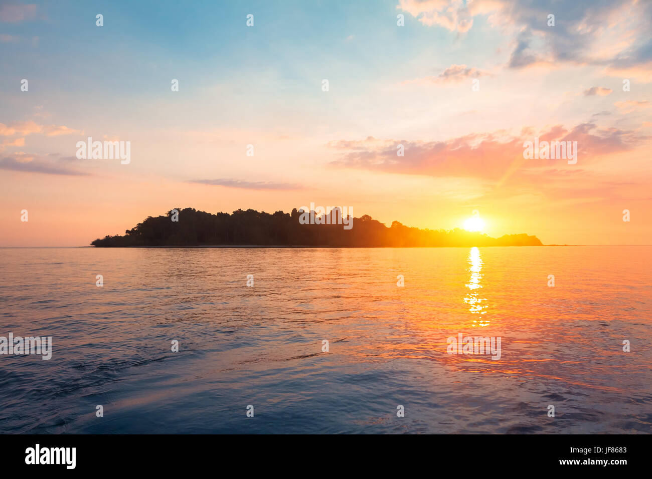 Silhouette einer tropischen Insel vom Meer Wasser umgeben am Horizont mit einem wunderschönen Sonnenuntergang Licht Stockfoto