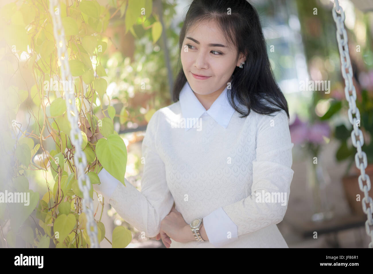 Junge attraktive Asiatin lächelnd im grünen Garten. Stockfoto