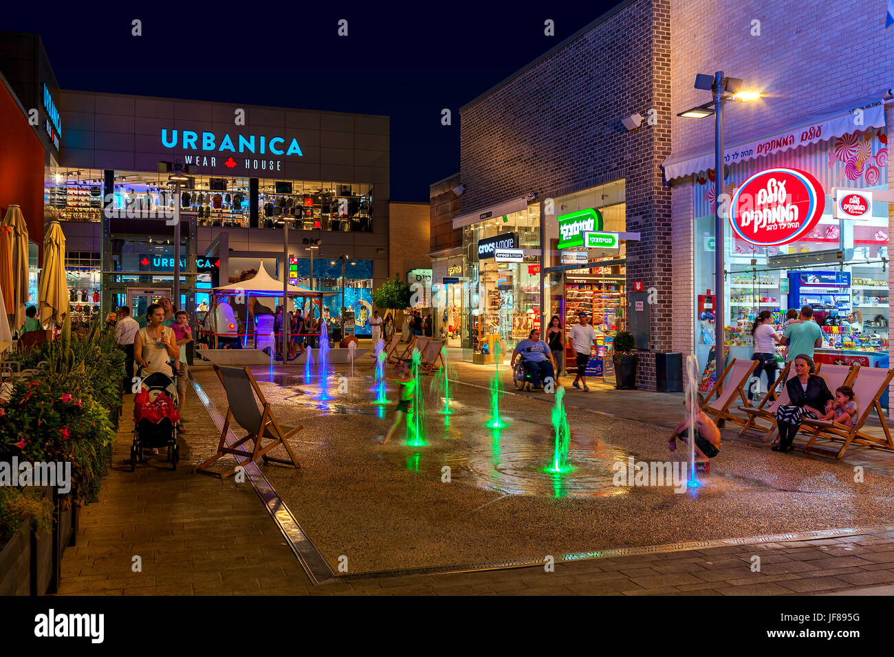 ASHDOD, ISRAEL - 3. Juli 2016: Geschäfte, Boutiquen und beleuchteten Springbrunnen in Openair Mall am Abend - im Besitz von großen Einkaufszentren Ltd., gegründet Stockfoto