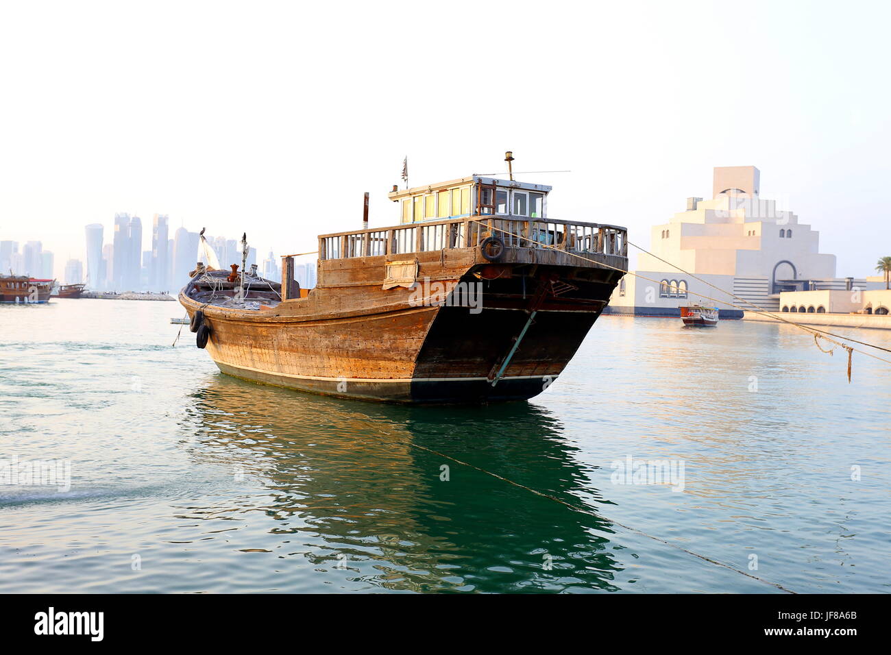 Eine große Handel Dhau gefesselt in den Hafen in der Nähe von Museum für islamische Kunst in Doha, Katar, 11. April 2017, mit Business-District-Skyline in der dis Stockfoto