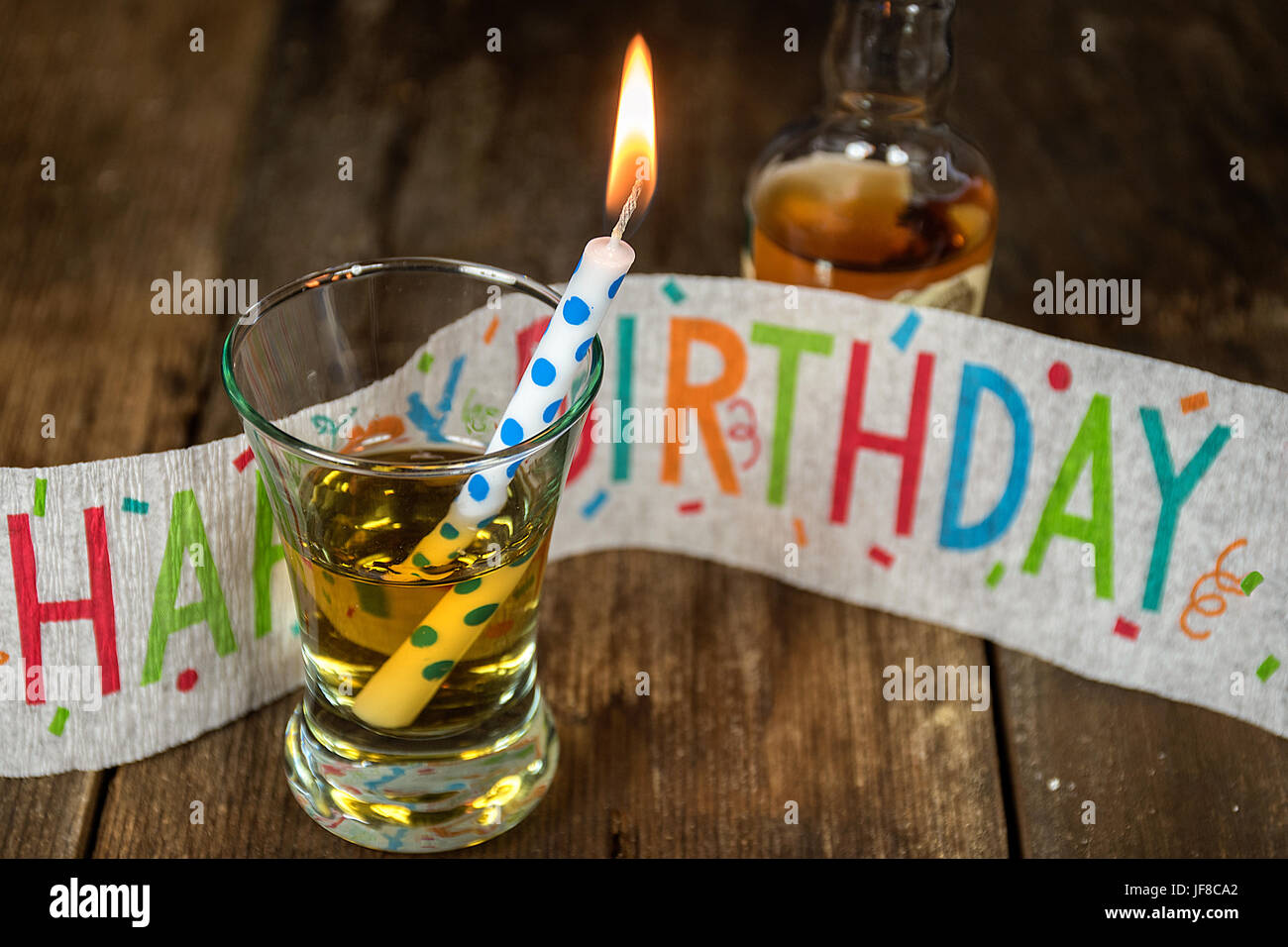 Geburtstag Kerze mit Whiskey in Schuss Glas und Geburtstag Banner auf rustikalen Holz Stockfoto