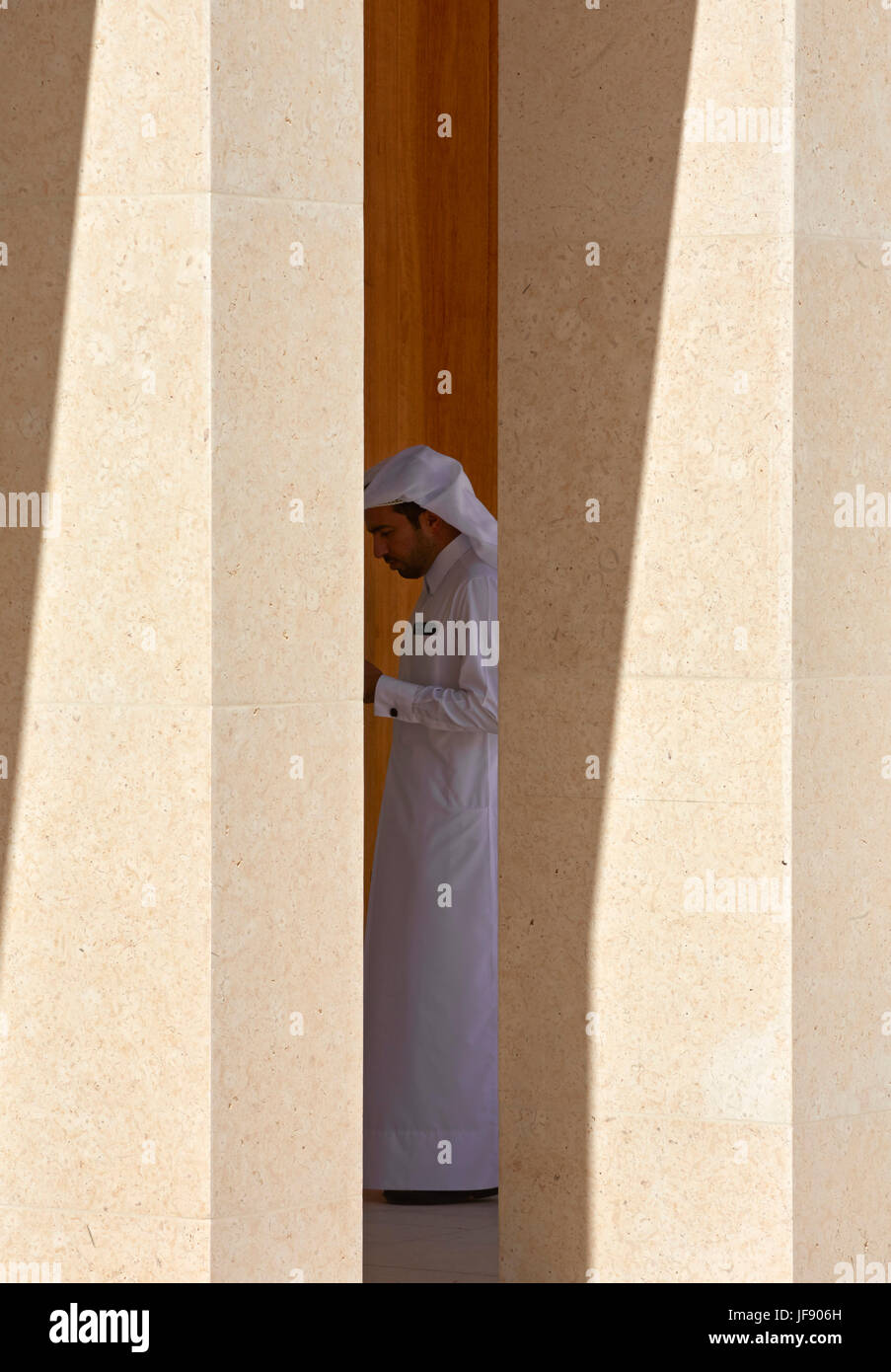 Mann in traditioneller Katar Kleid durch Spalten mit starken Schatten. Mohammed Bin Jassim Haus, Doha, Katar. Architekt: John McAslan & Partner, 2 Stockfoto