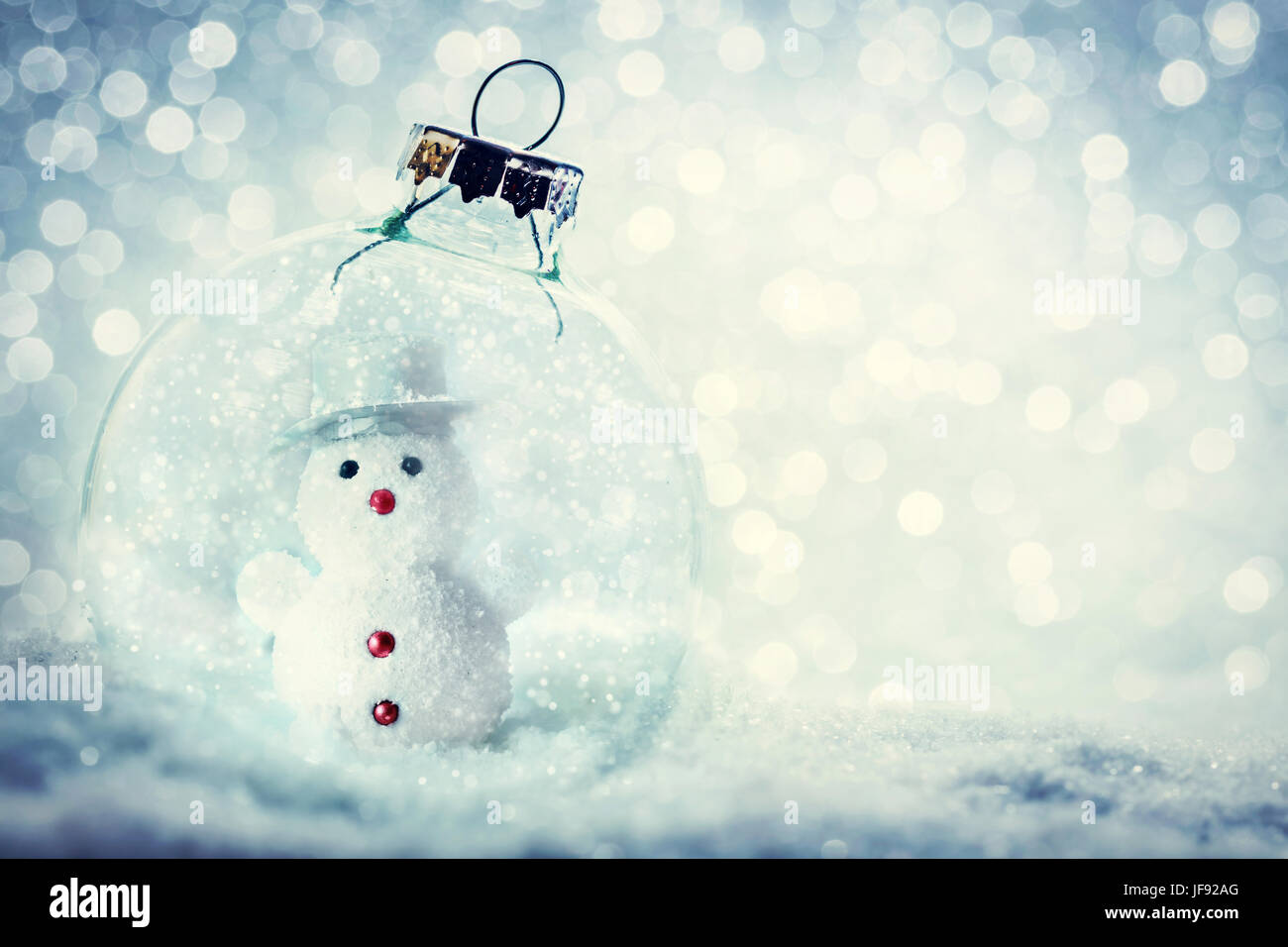 Glas Weihnachtskugel mit Schneemann im Inneren. Schnee, Glitzer Hintergrund. Stockfoto