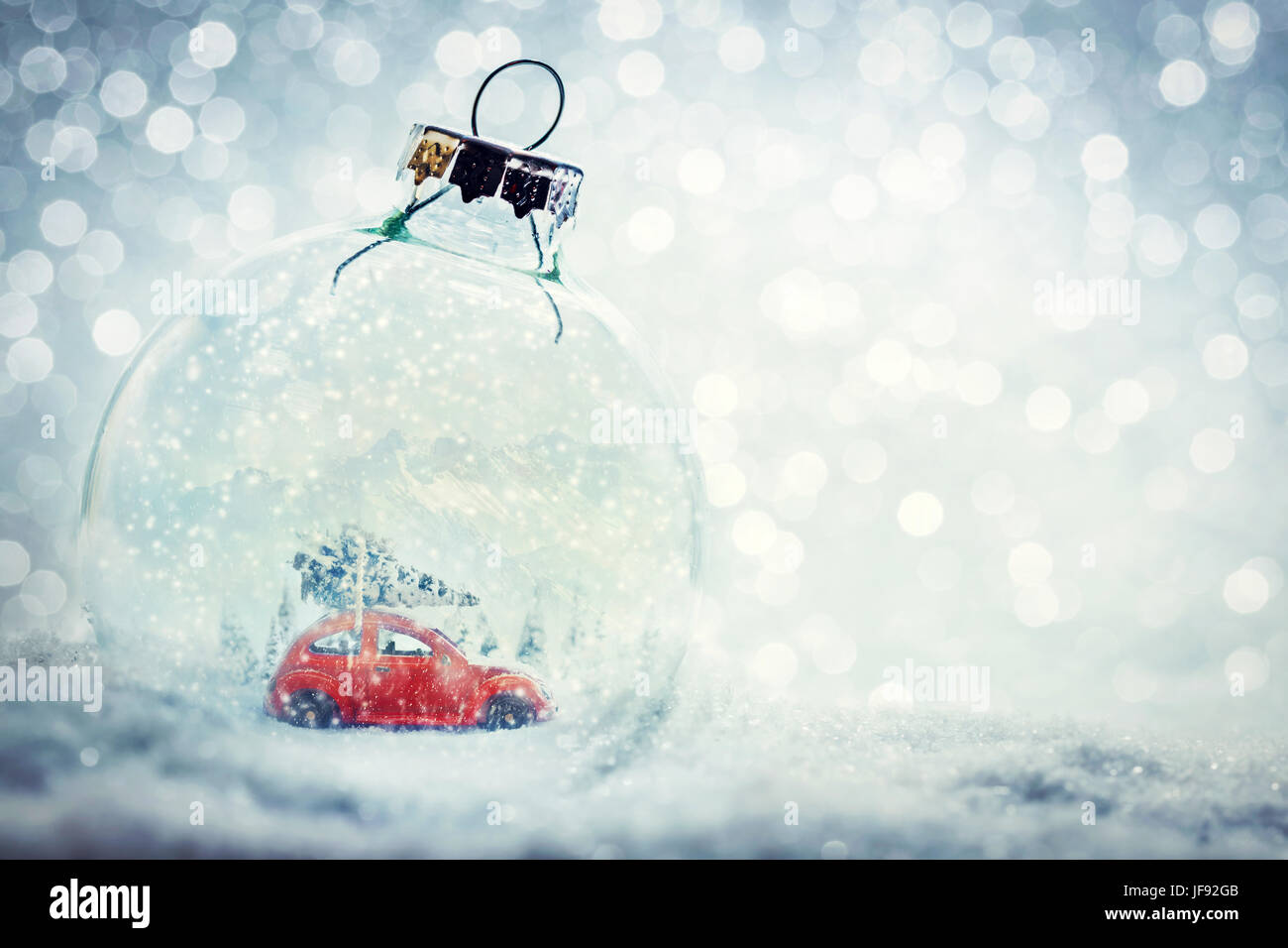 Weihnachtskugel Glas im Schnee mit Miniatur-Winterwelt in - Auto mit Weihnachtsbaum, Berge. Glitter-Hintergrund. Stockfoto