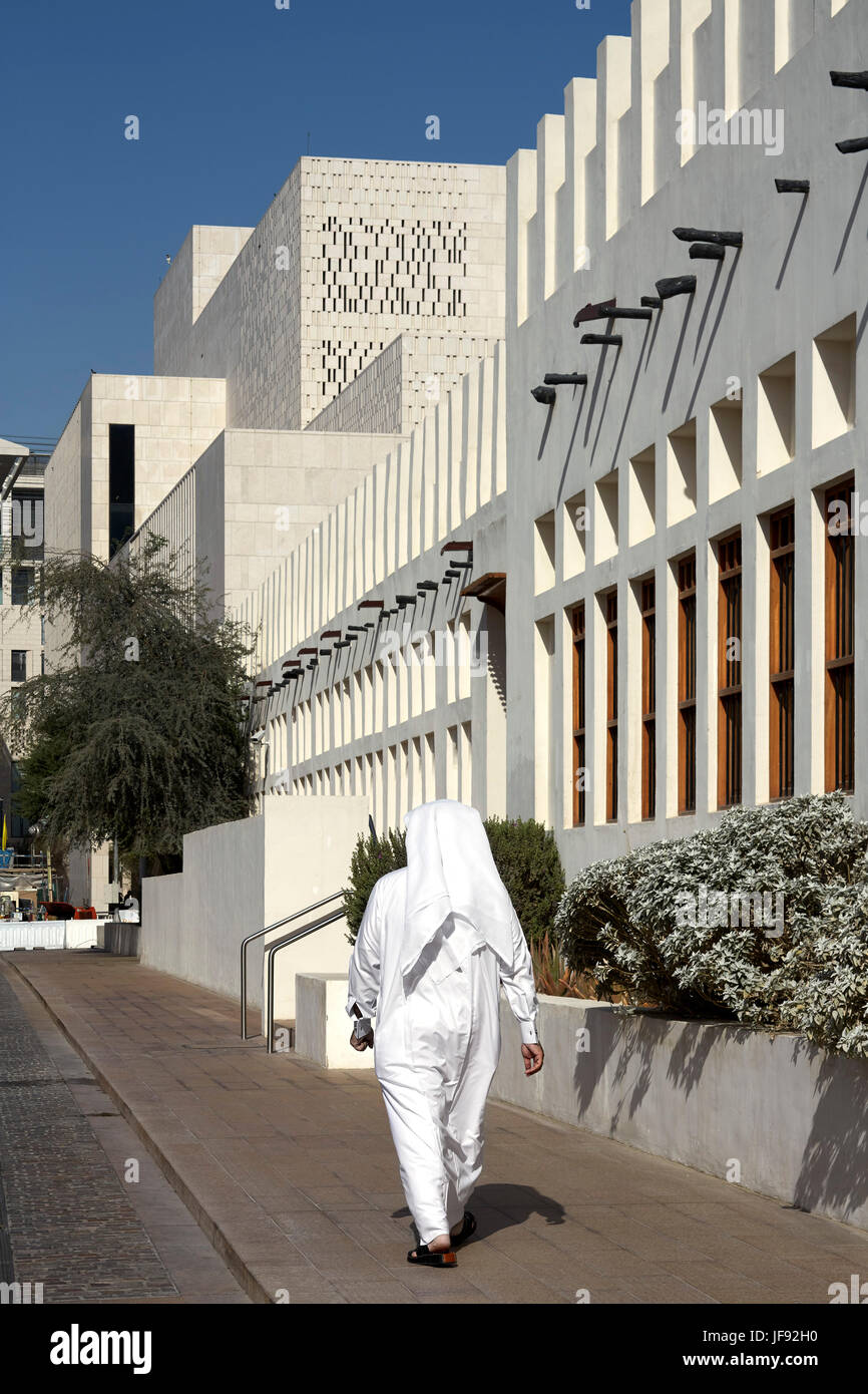 Lokale Qatari Mann in traditioneller Kleidung, die zu Fuß in Richtung Eingang. Bin Jelmood Haus, Doha, Katar. Architekt: John Macaslan und Partner, 2017. Stockfoto