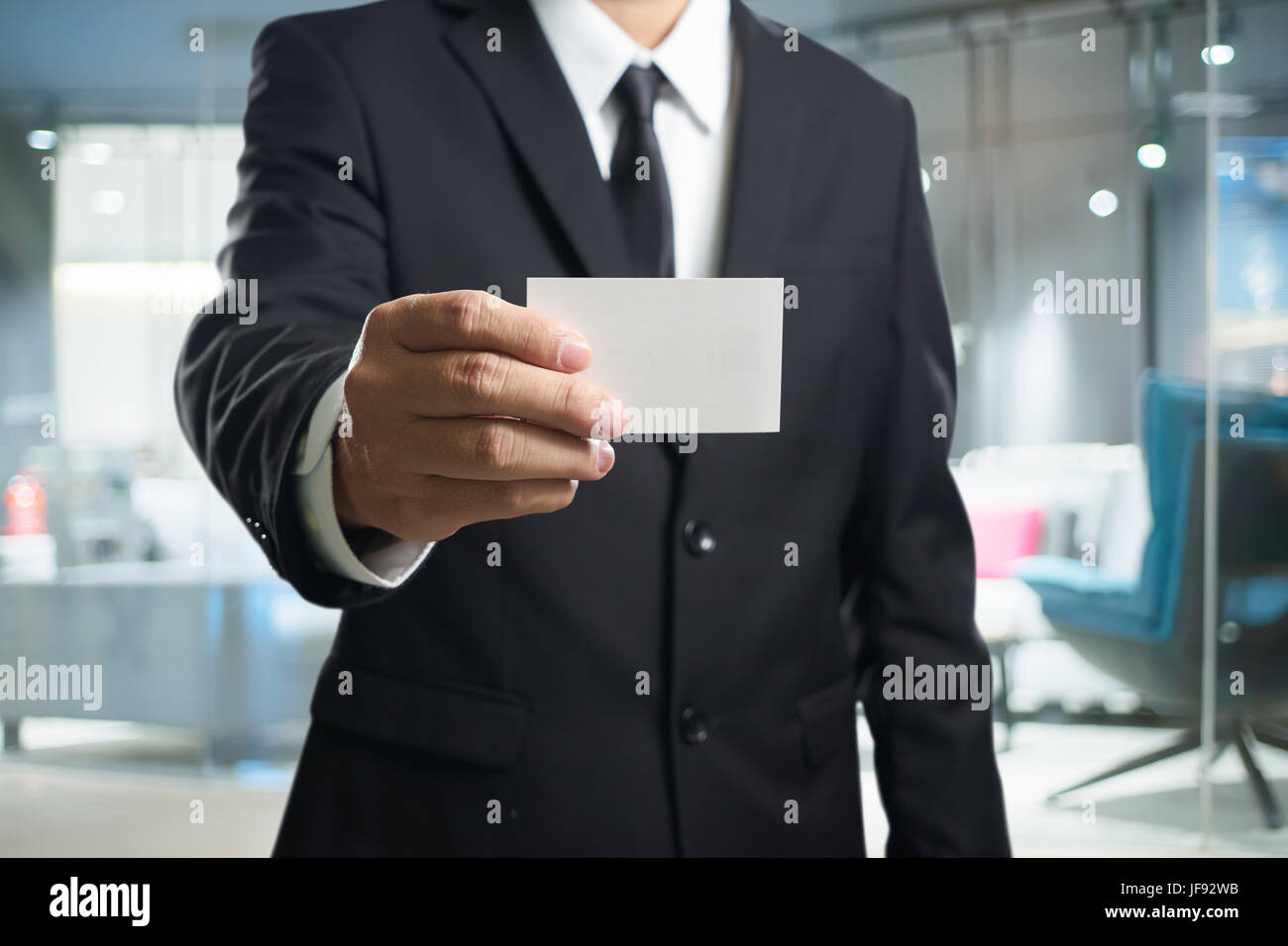Intelligente Geschäftsmann im schwarzen Anzug mit zeigen die Namen Karte Pose. Stockfoto