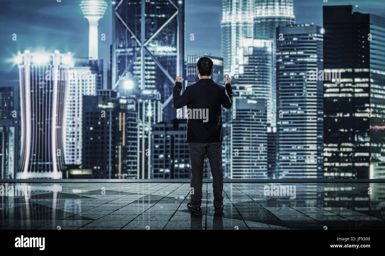 Rückansicht des aufgeregt Geschäftsmann mit Arme nach oben, verschwommene Morden Skyline der Stadt. Stockfoto