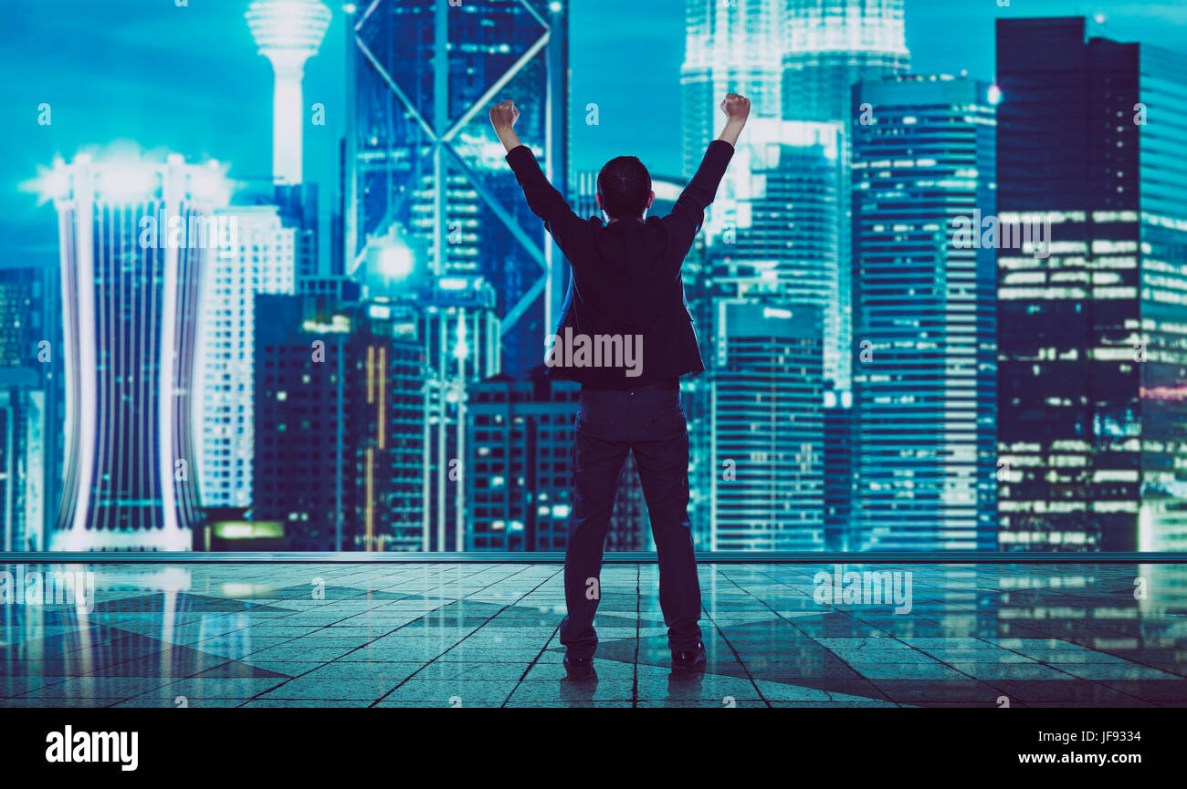 Rückansicht des aufgeregt Geschäftsmann mit Arme nach oben, verschwommene Morden Skyline der Stadt. Stockfoto