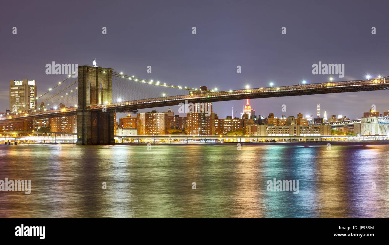 Panorama-Foto von der Brooklyn Bridge mit Lichter der Stadt spiegeln sich in East River bei Nacht, New York City, USA. Stockfoto
