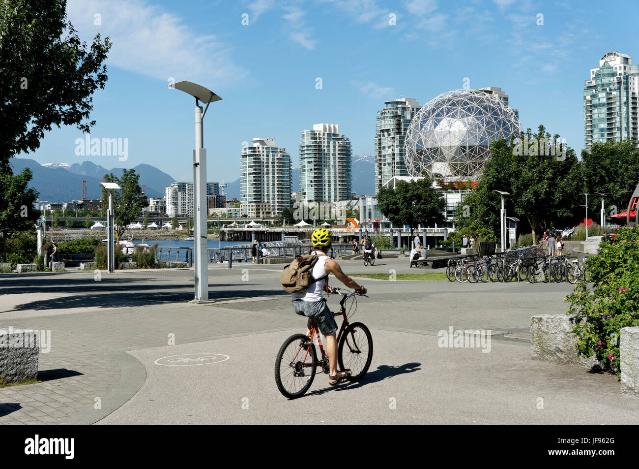 Junger Mann reiten Fahrrad mit TELUS World of Science Dome in zurück in das Dorf auf False Creek, Vancouver, British Columbia, Kanada Stockfoto