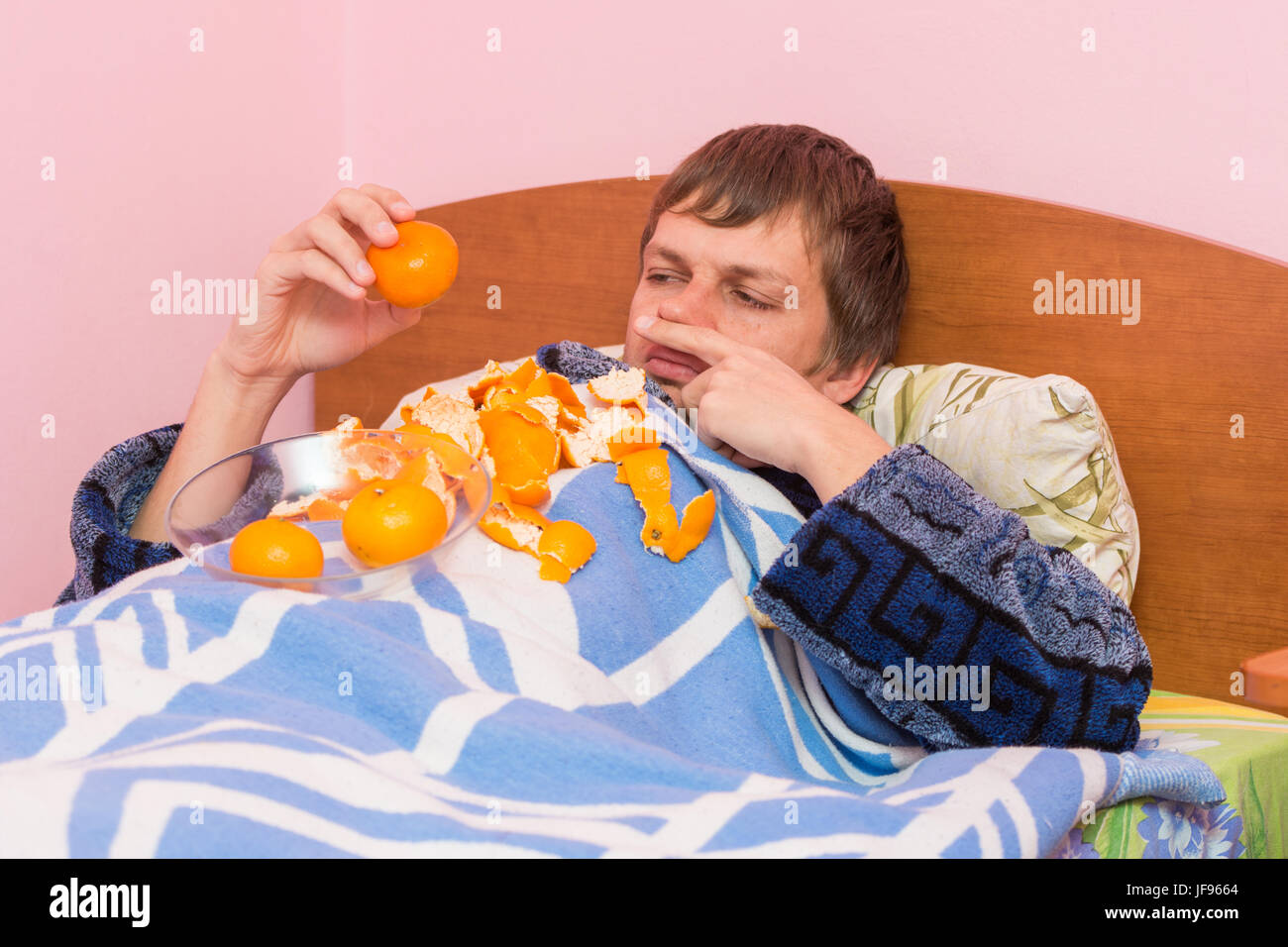 Ein Mann, der Mandarinen krank im Bett liegt Stockfoto