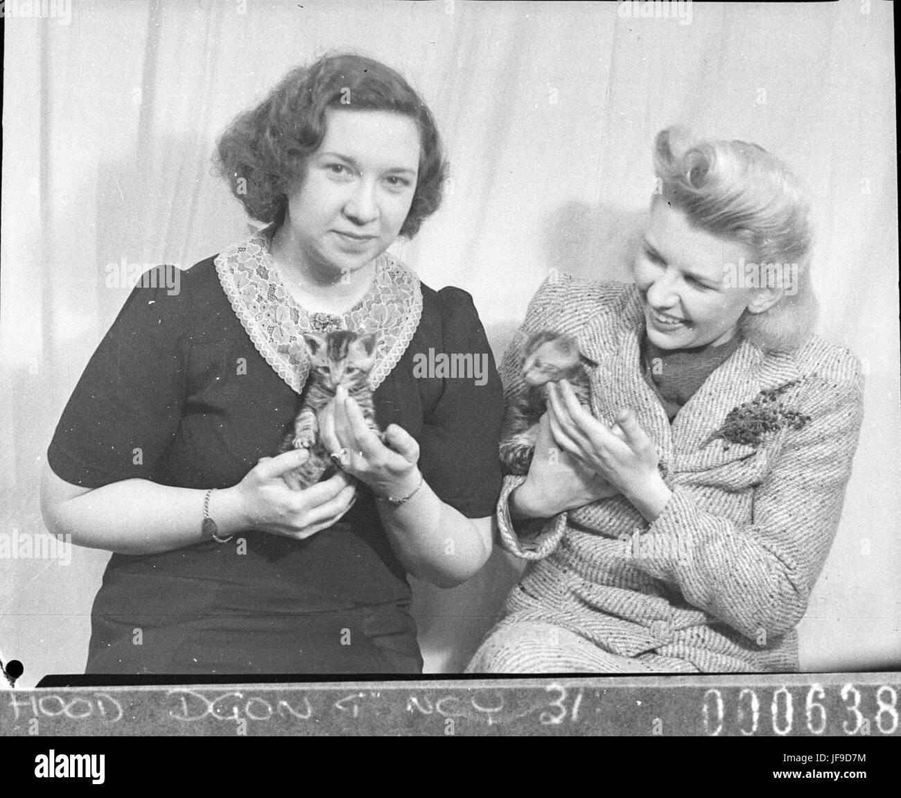 Eine bezaubernde Szene aus dem Film *diese*, in der zwei Schauspielerinnen kleine Kätzchen halten, die einen Moment der Unbeschwertheit und der Interaktion mit den Charakteren festhalten. Stockfoto