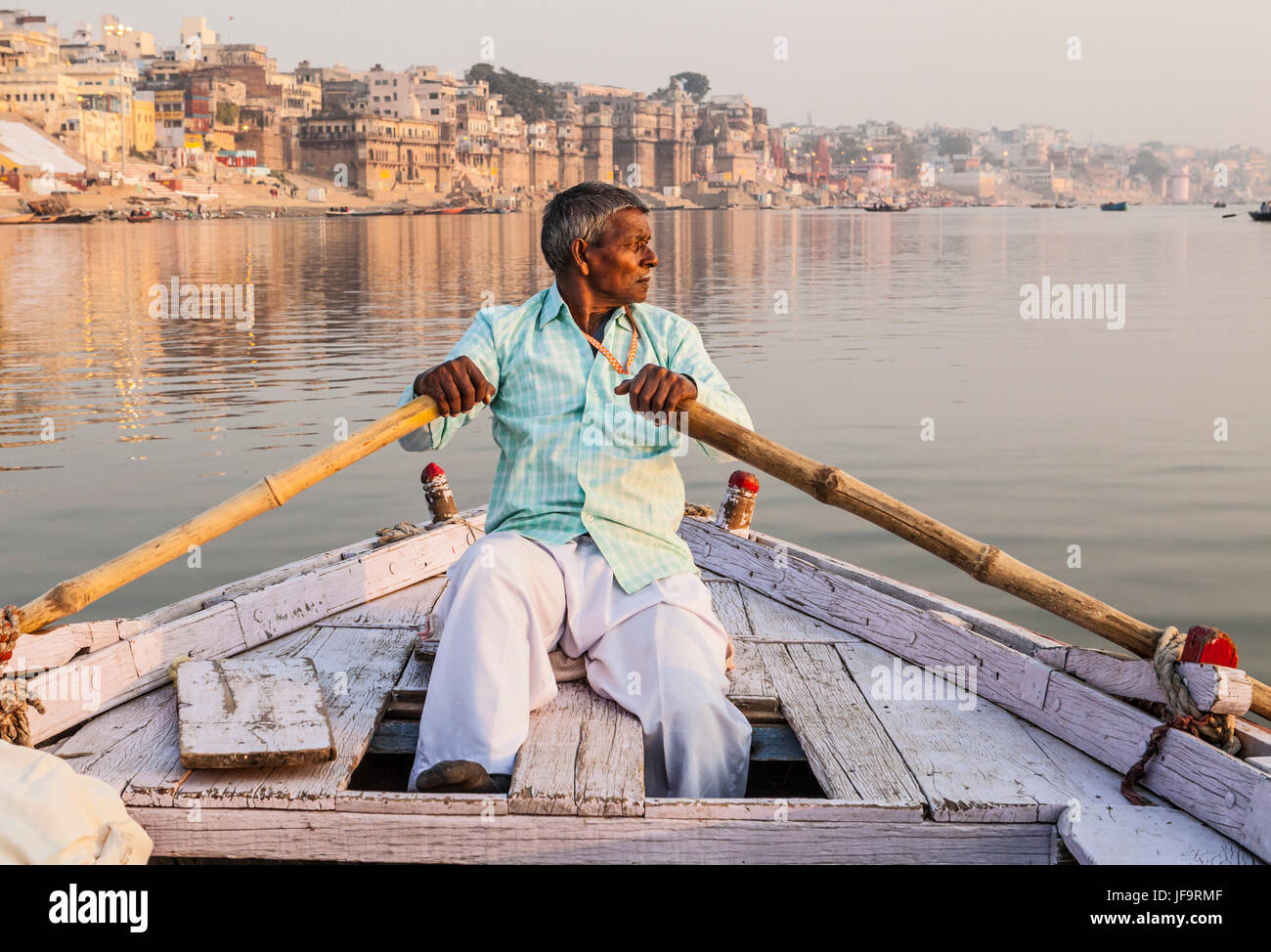 Ein indischer Mann ein Ruderboot für Ausflüge auf den Ganges, Varanasi, Indien. Stockfoto