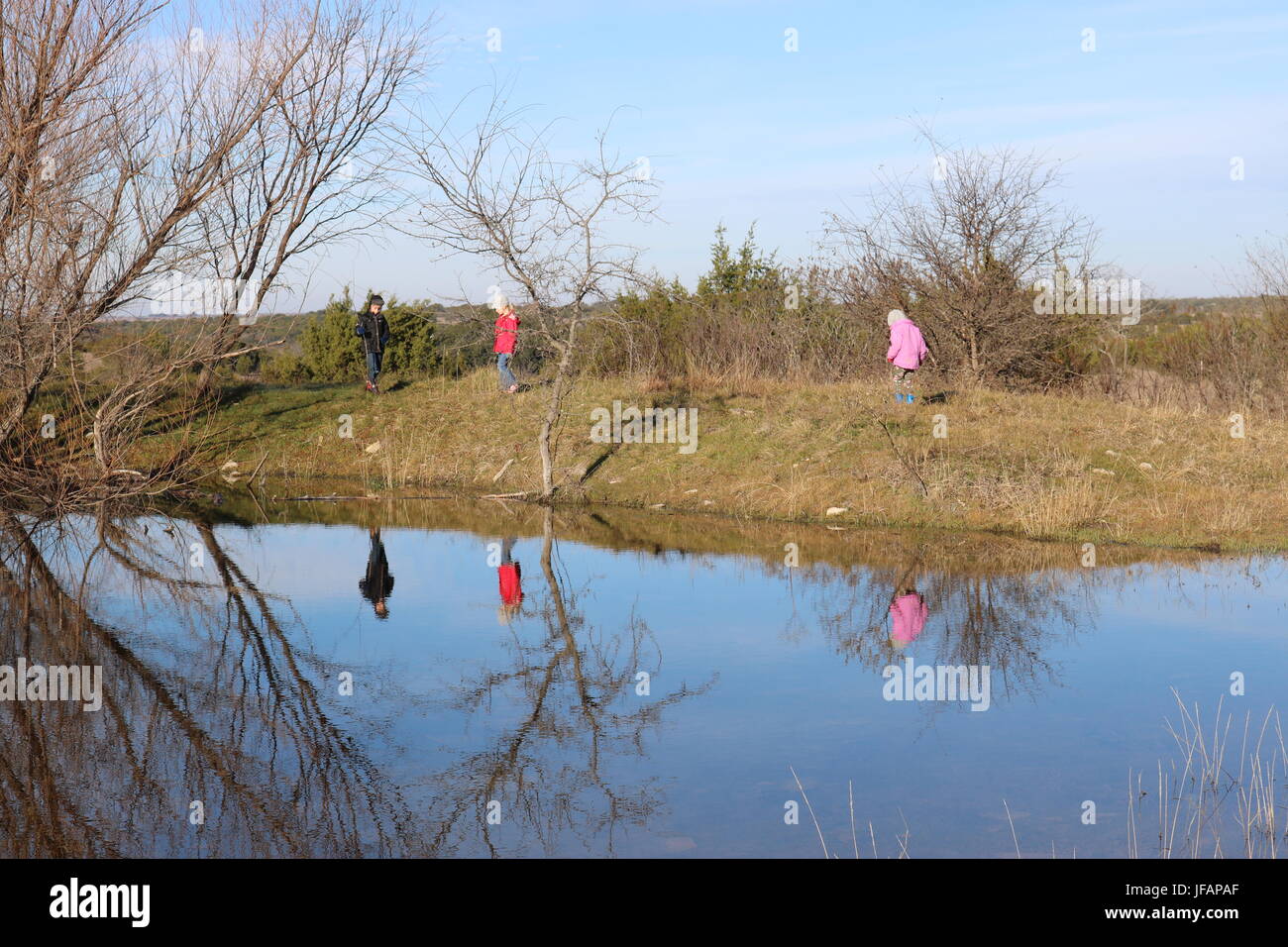 Drei Kinder, die Wanderung auf der Ranch mit dem Wasserloch in Texas im winter Stockfoto