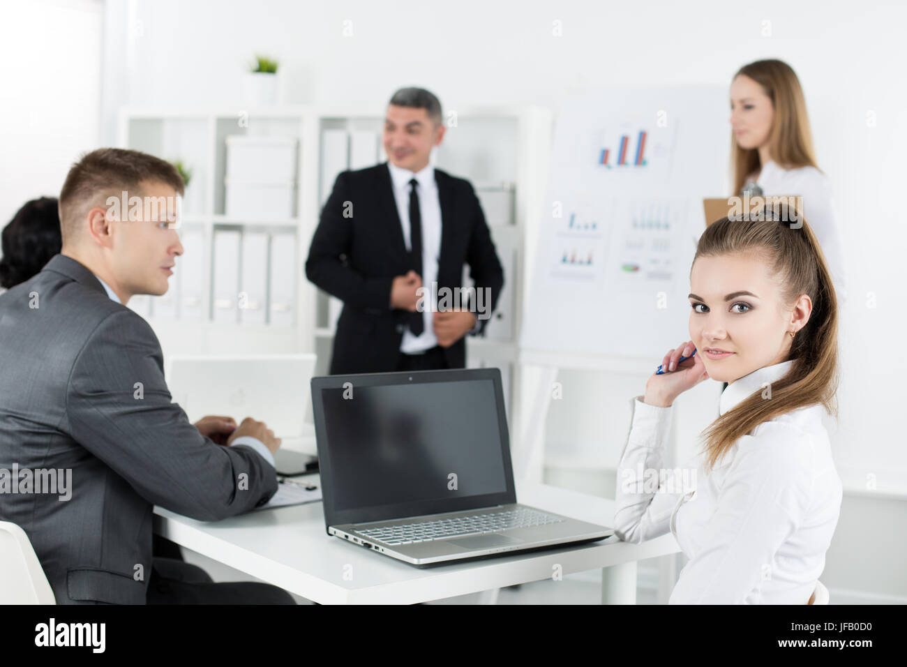 Geschäftsleute treffen sich in Büro, Projekt zu diskutieren. Junge hübsche weibliche Büroangestellte Blick in die Kamera mit ihren Kollegen auf Hintergrund. Bus Stockfoto