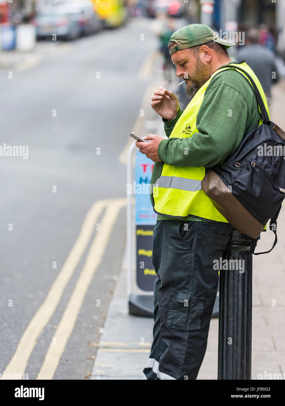 Seitenansicht eines kaukasischen Mannes mittleren Alters, der in Großbritannien auf der Straße raucht. Stockfoto
