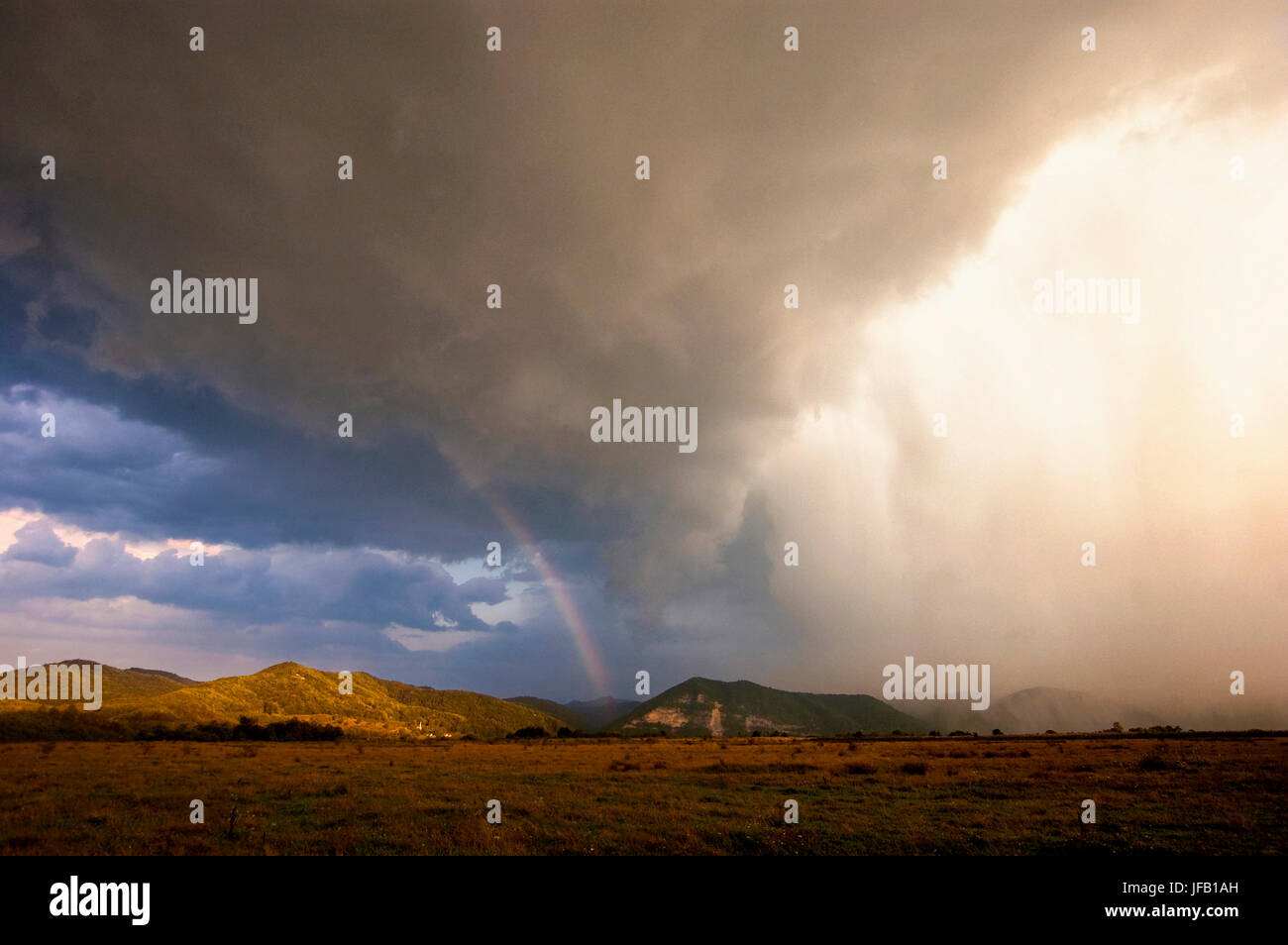extreme Wetterereignisse Landschaft mit dramatischen Gewitterwolken, Starkregen und Regenbogen im Abendlicht Stockfoto