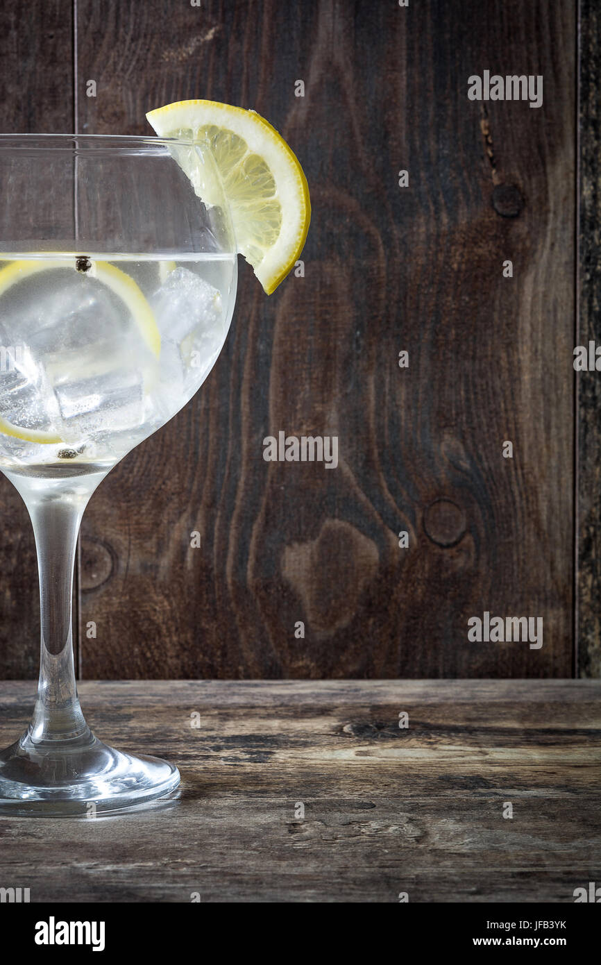 Glas von Gin Tonic mit Zitrone auf hölzernen Hintergrund Stockfoto