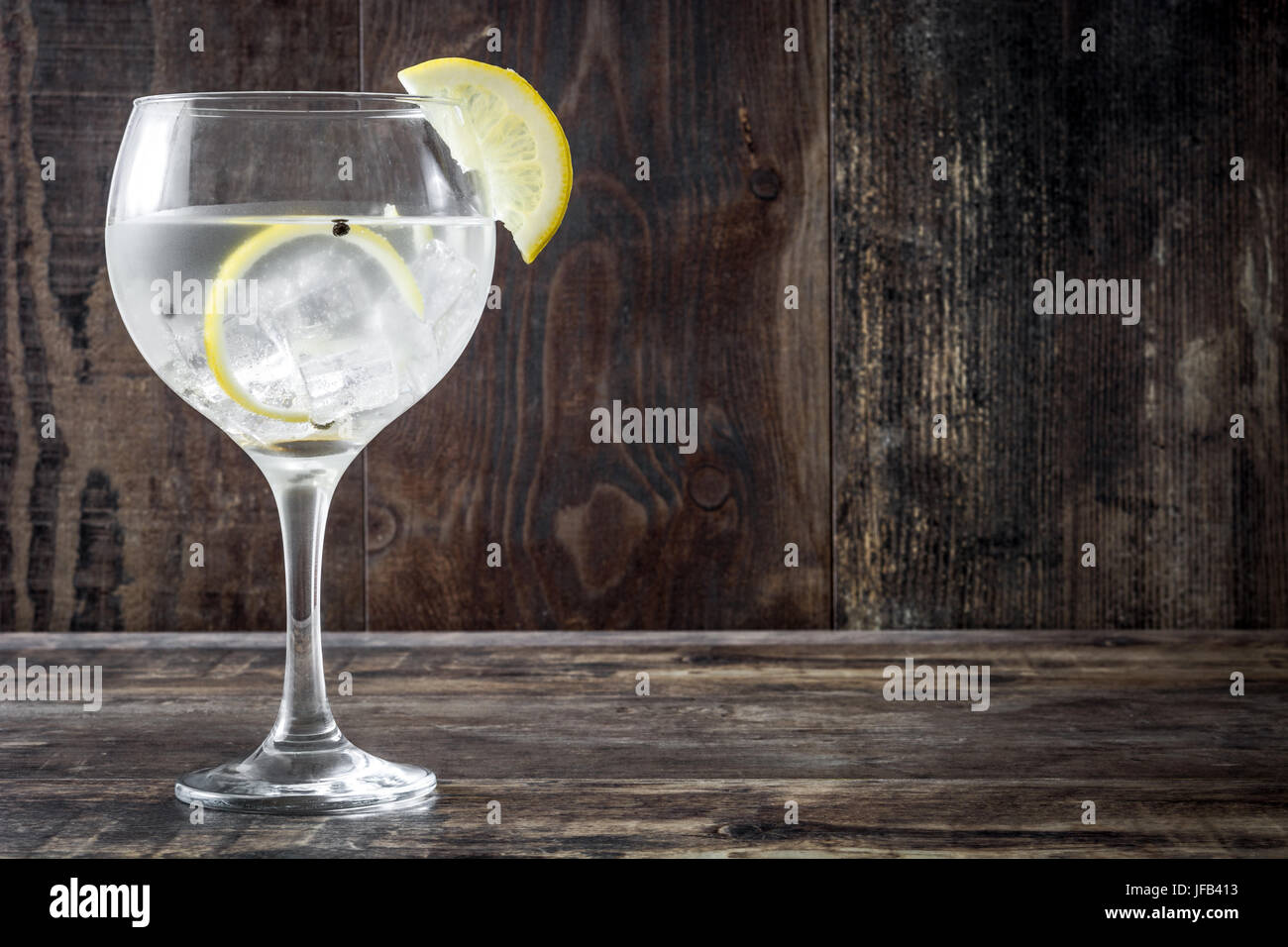 Glas von Gin Tonic mit Zitrone auf hölzernen Hintergrund Stockfoto