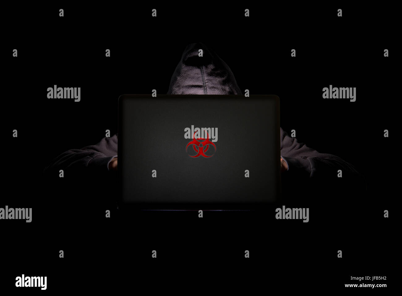 Eine Person in einem dunklen Raum mit einem Laptop mit rotem Biohazard-Logo, Internet-Phishing, Hacking und Diebstahl persönlicher Daten sowie Bedrohungen der Datensicherheit Stockfoto