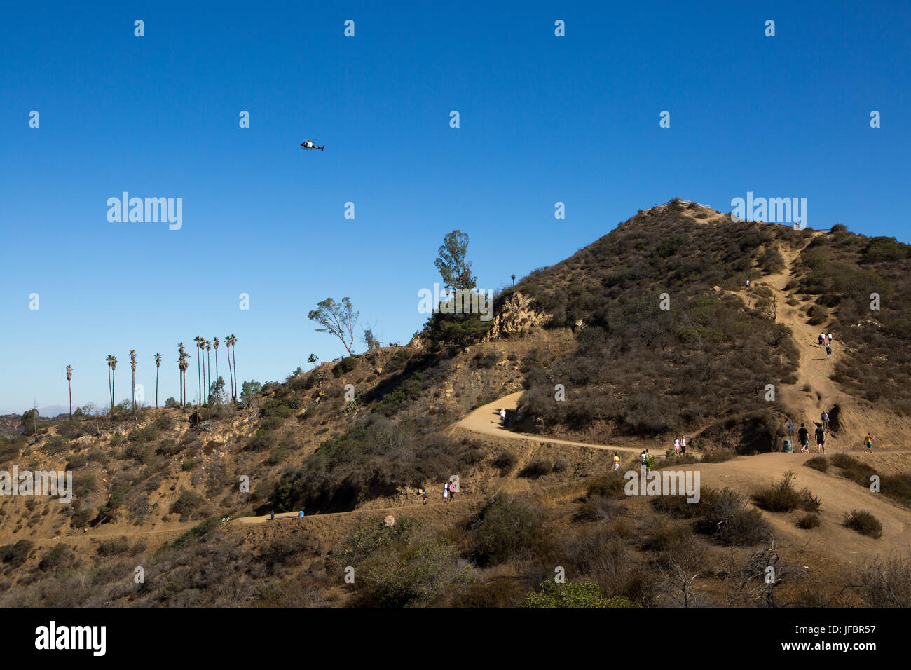 Ein Helikopter fliegt über Wanderer in den Hügeln außerhalb von Los Angeles und Hollywood, in der Nähe des Griffith Observatorium. Stockfoto