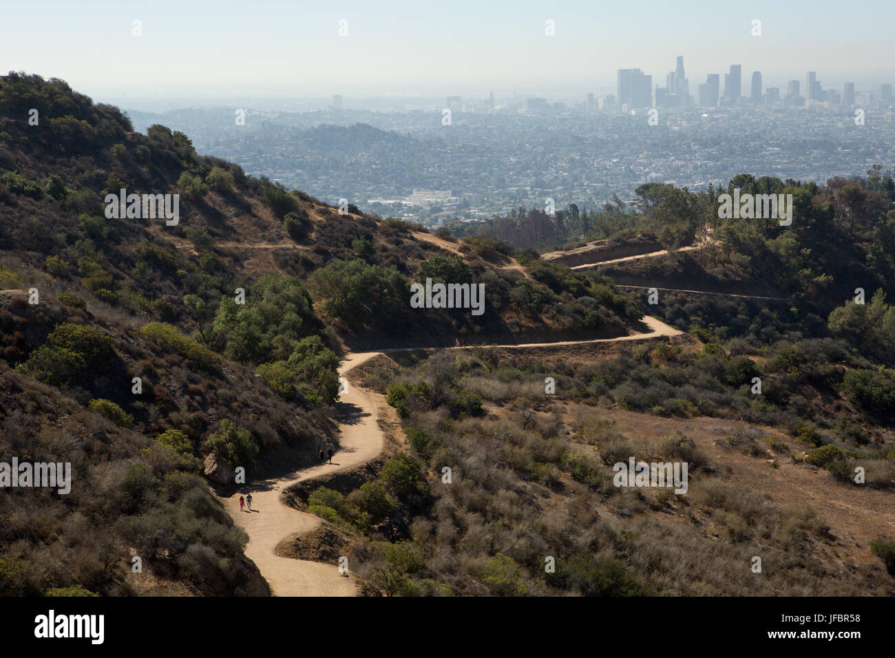 Folgen Wanderer einen gewundenen Pfad in die Hollywood Hills. Verunreinigung der Luft hängt über Los Angeles. Stockfoto